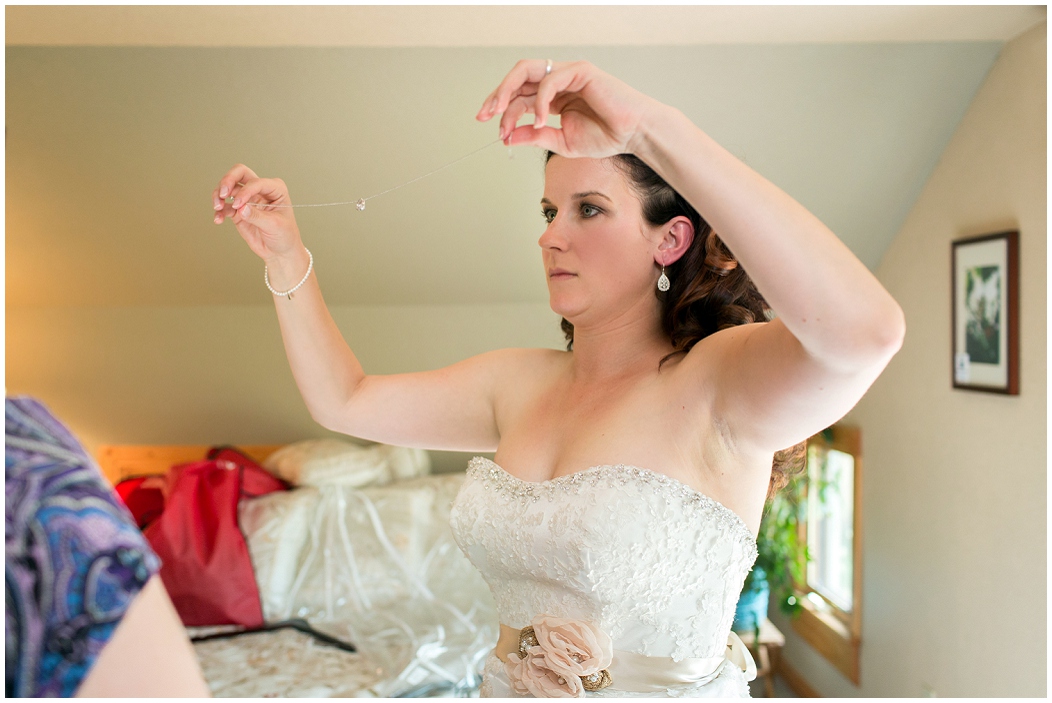 picture of bride putting on her necklace