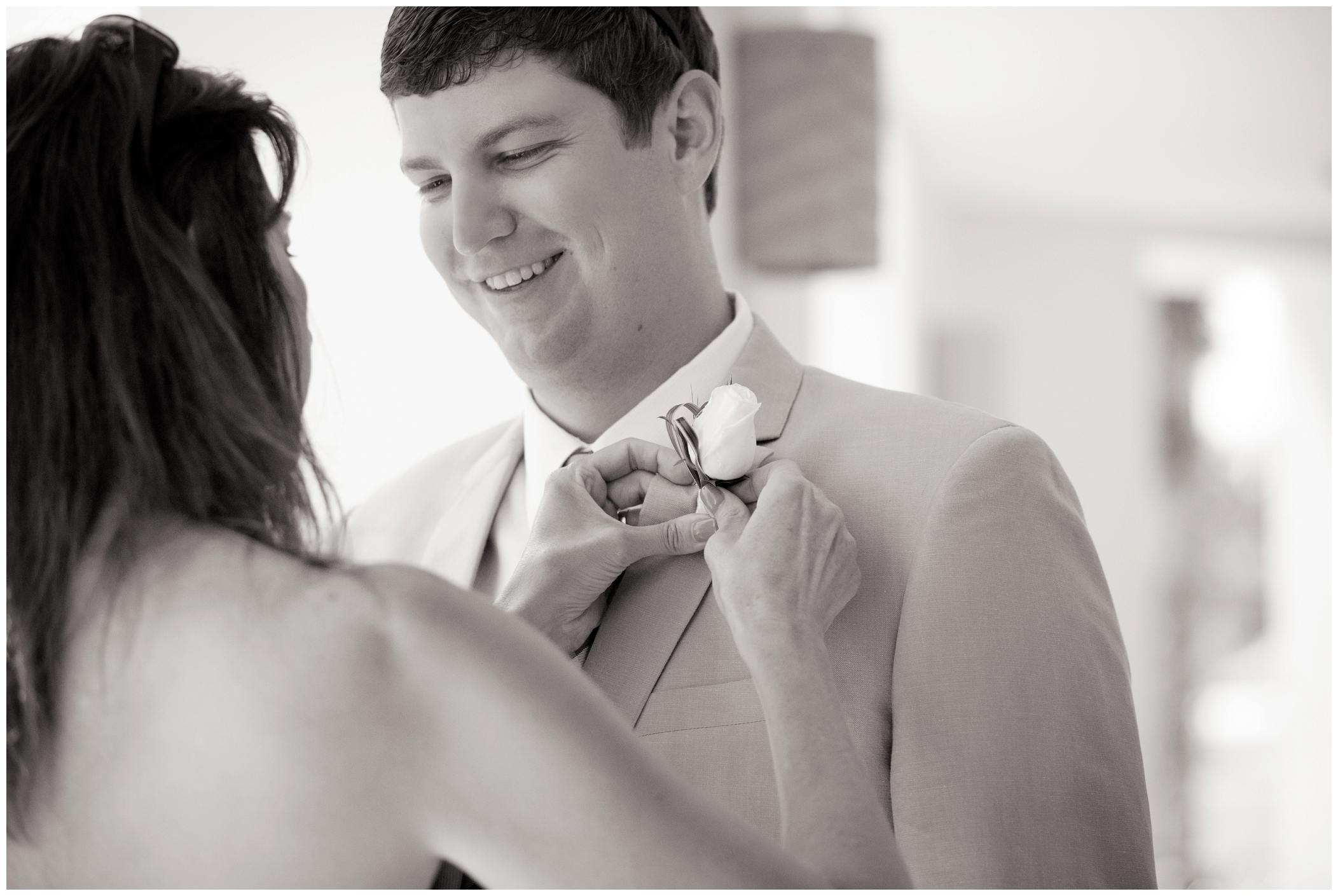 picture of groom's mom putting on groom's boutonniere 