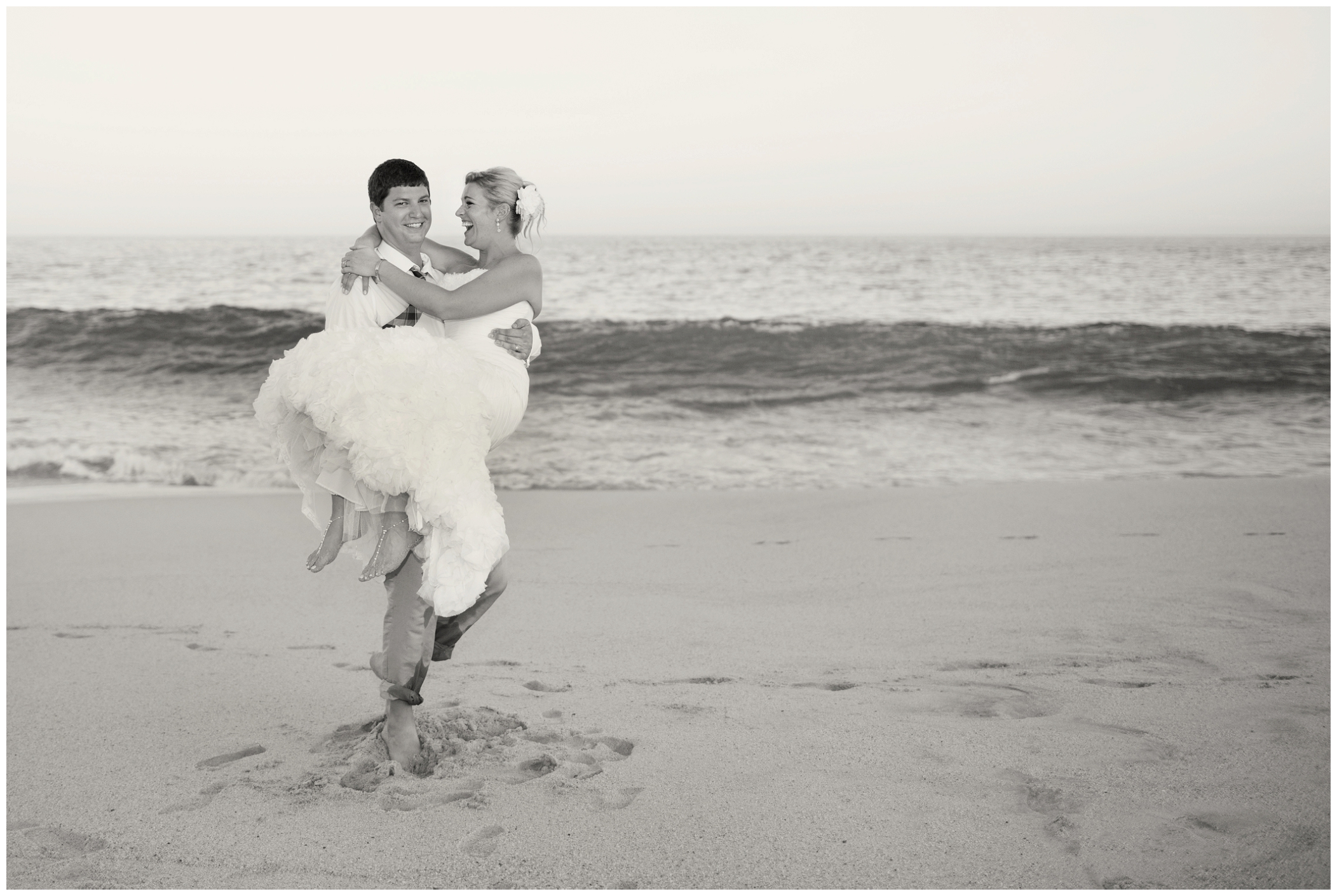 picture of groom carrying bride on the beach 