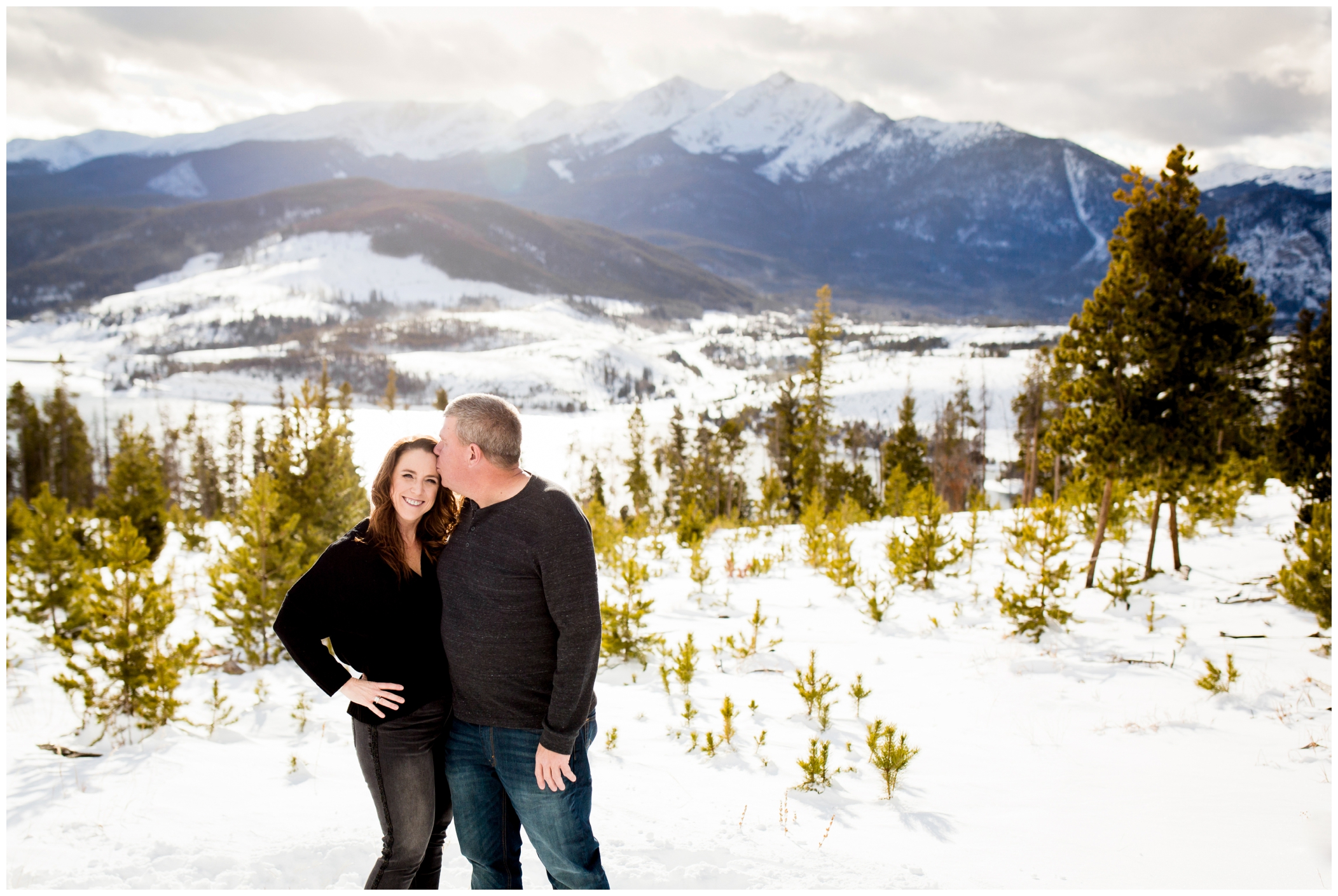 mom and dad posing for snowy winter family photographs in the Breckenridge Colorado mountains