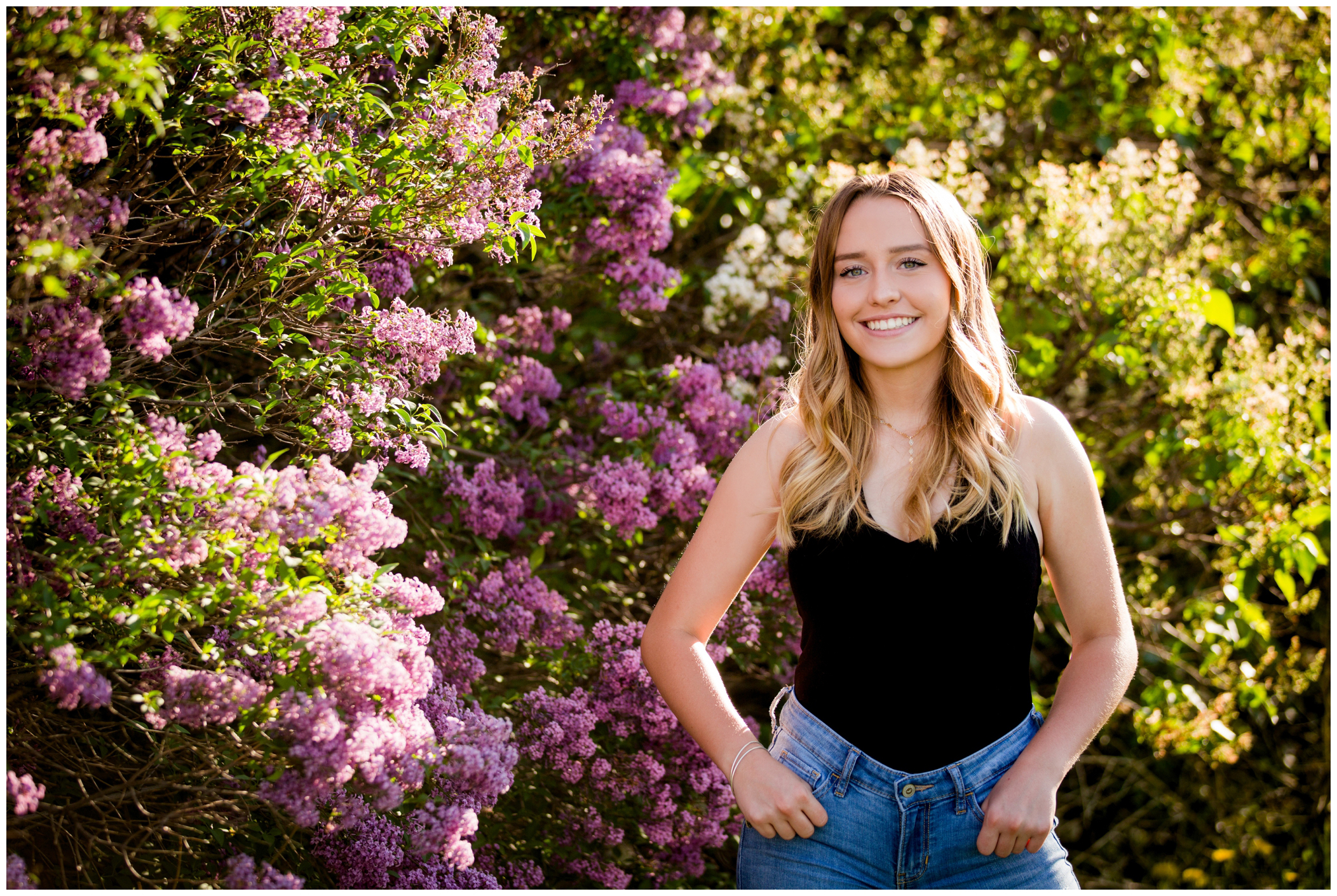 Longmont high school senior posing against a colorful lilac bush in spring 