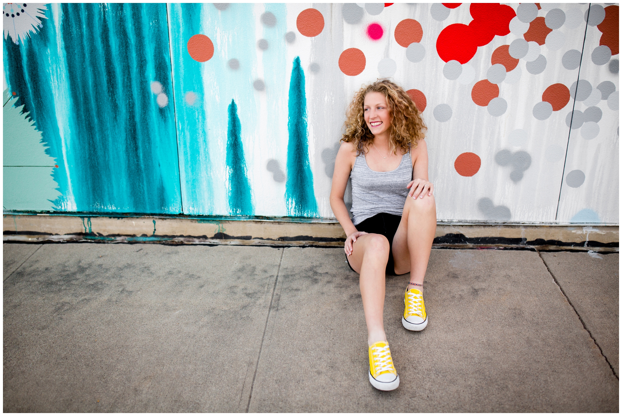 girl in converse sitting against graffiti wall at Longmont senior pictures 