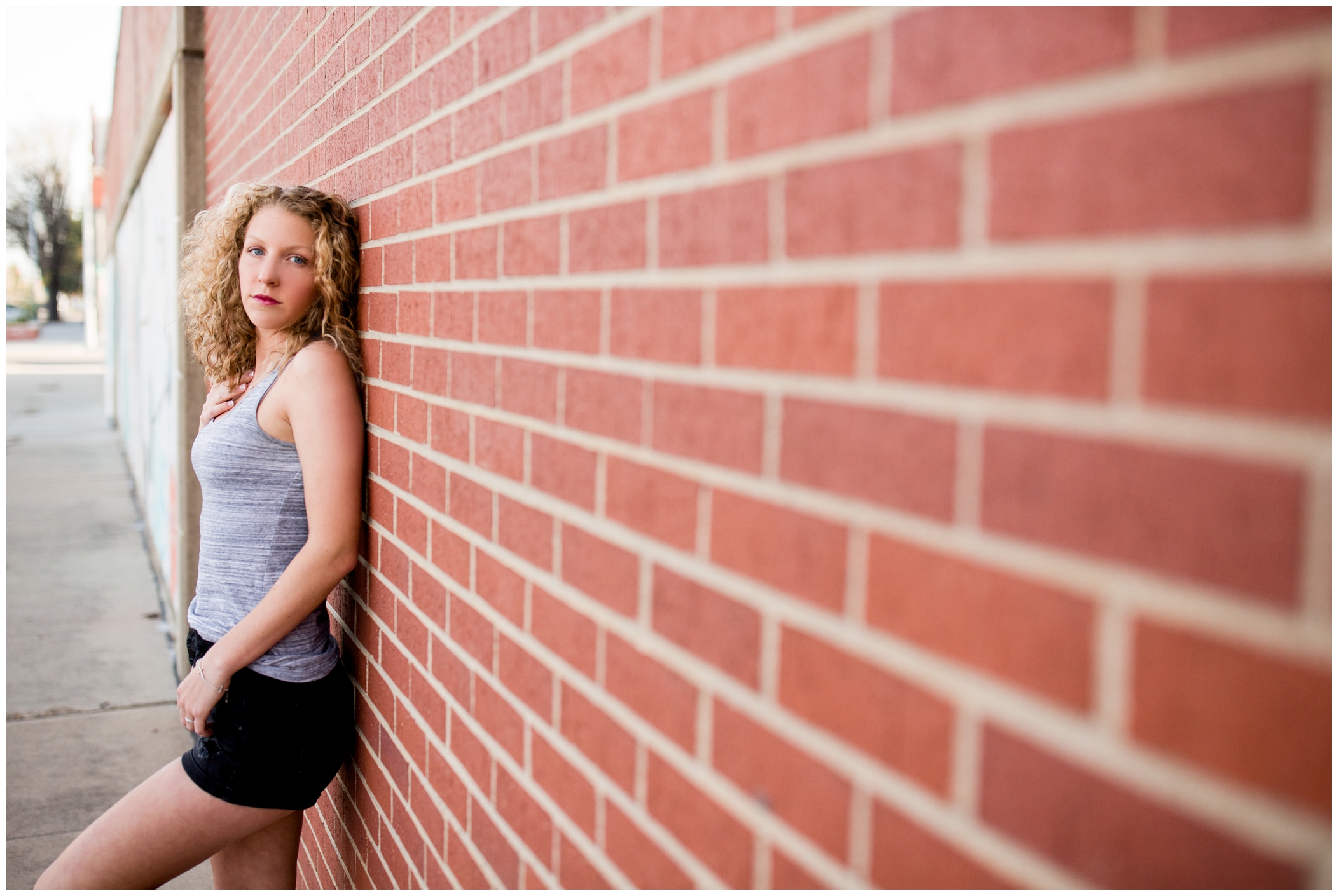 girl leaning on brick wall during her mead high school senior pictures 