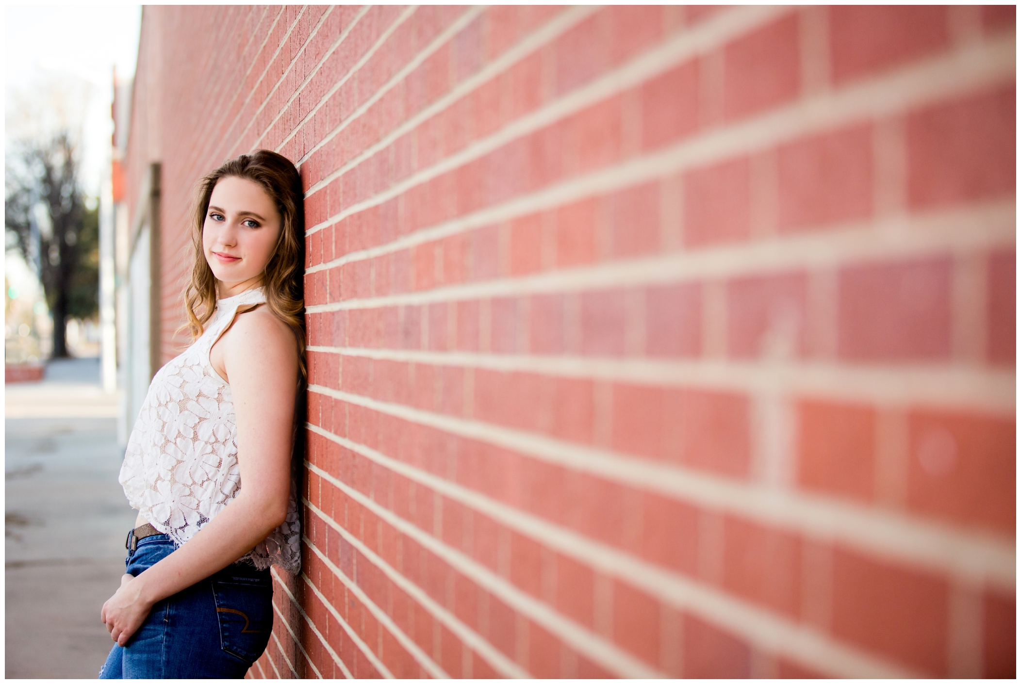Silver Creek High School Colorado senior leaning against a brick wall during her senior portraits 
