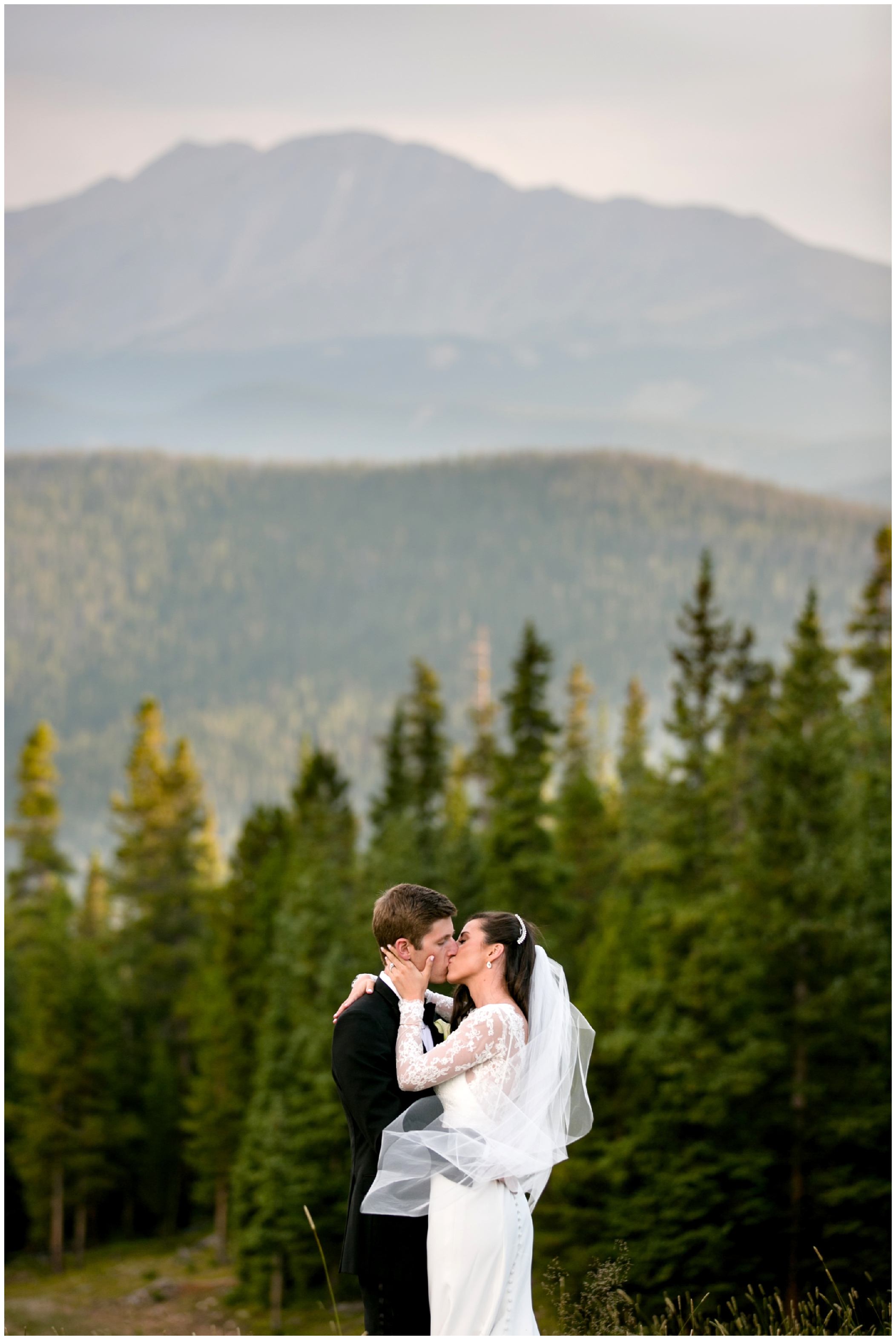 bride and groom kissing with mountains in background at Timber Ridge Lodge Keystone Colorado wedding photos 