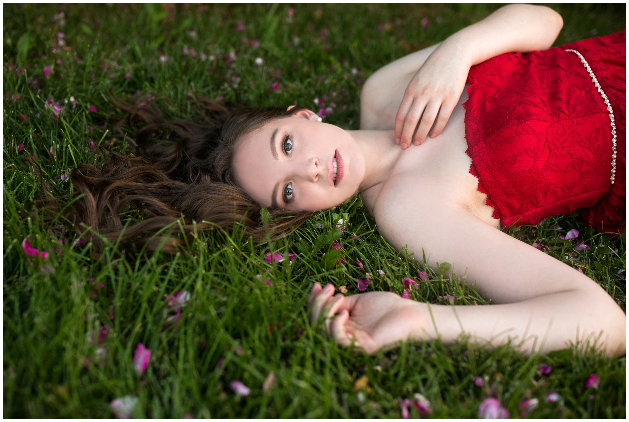 girl with long hair laying in grass during longmont senior photos