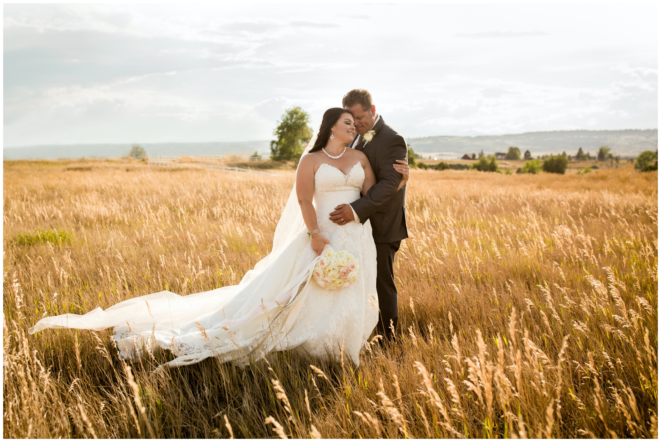 bride and groom hugging in a field at Berthoud Colorado rustic glam wedding