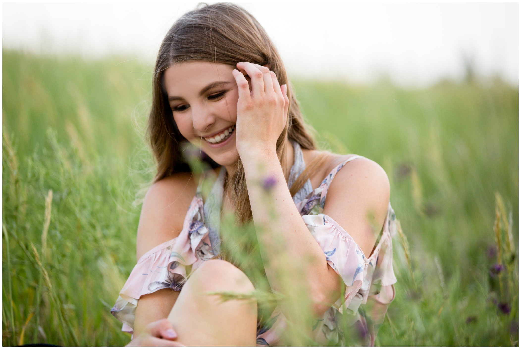 girl laughing and sitting in flowers during Westminster Colorado senior pictures 