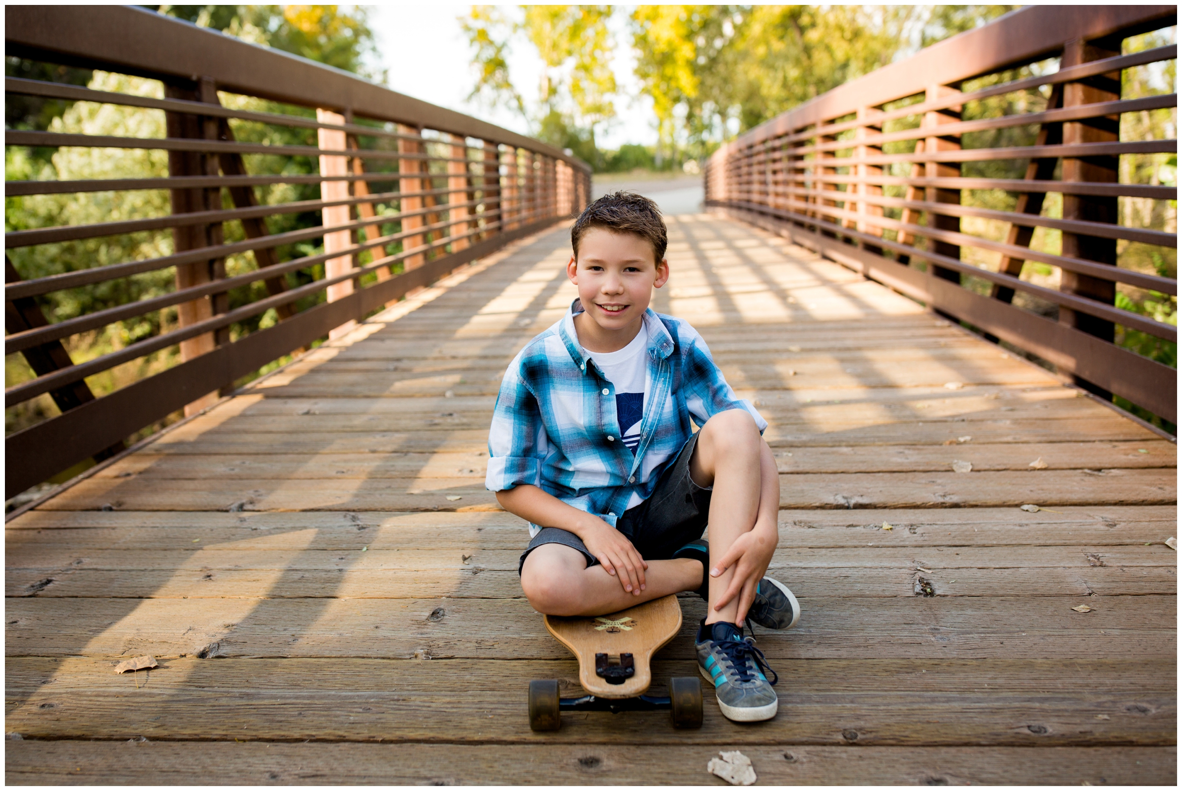 boy sitting on skateboard at Longmont Colorado family photography session at Golden Ponds 