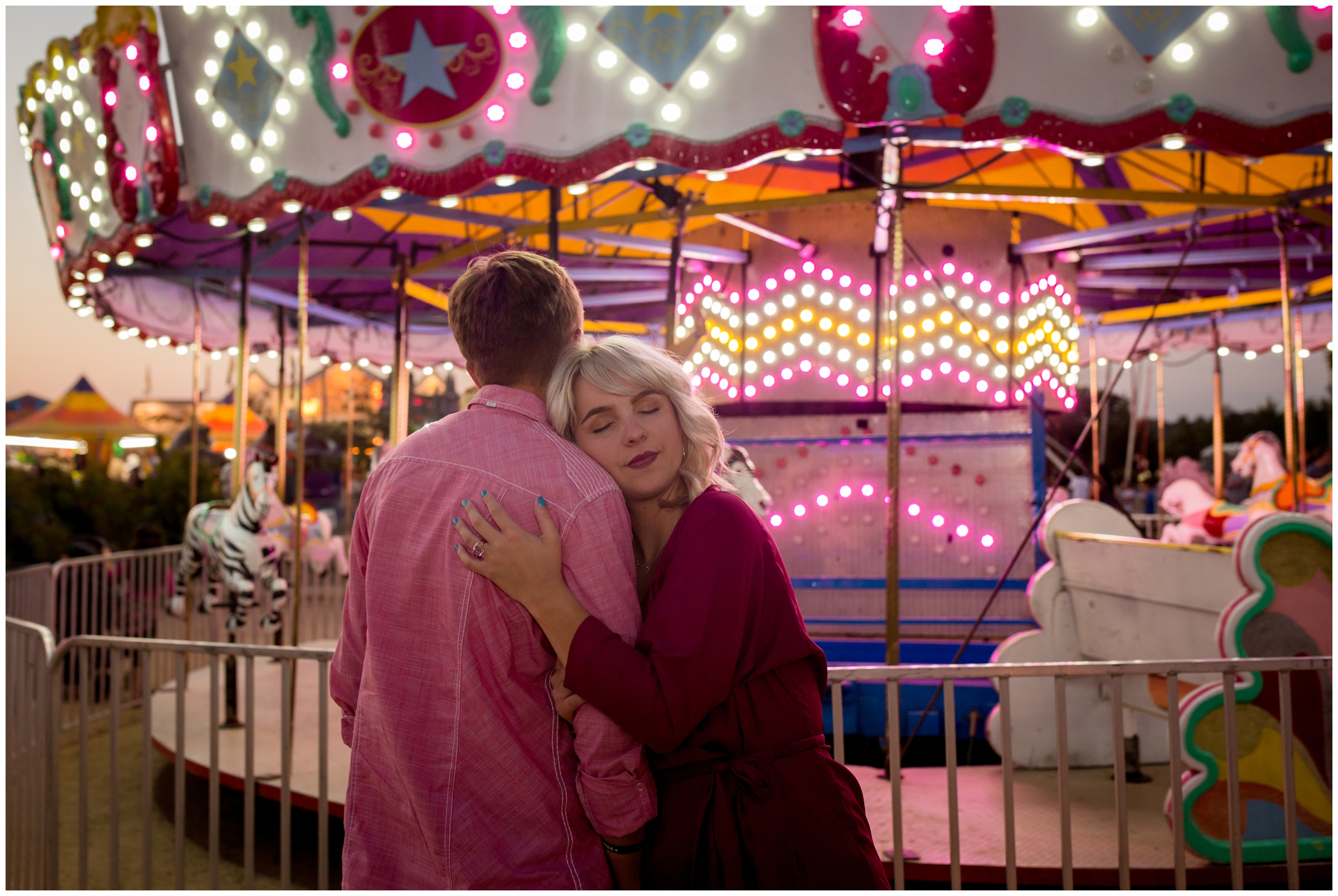 couple standing next to merry-go-round at their Boulder County Fairgrounds Longmont engagement portraits 