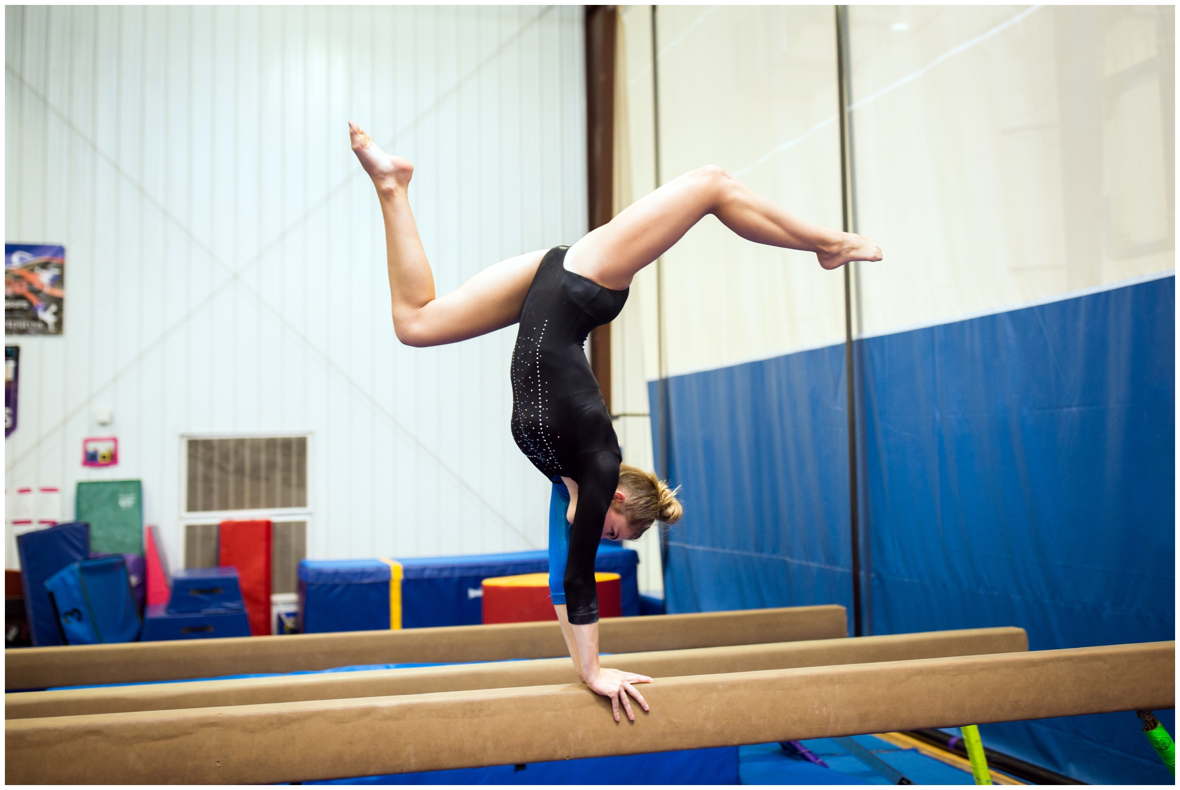female gymnast doing handstand on balance beam during gymnastics senior photography session
