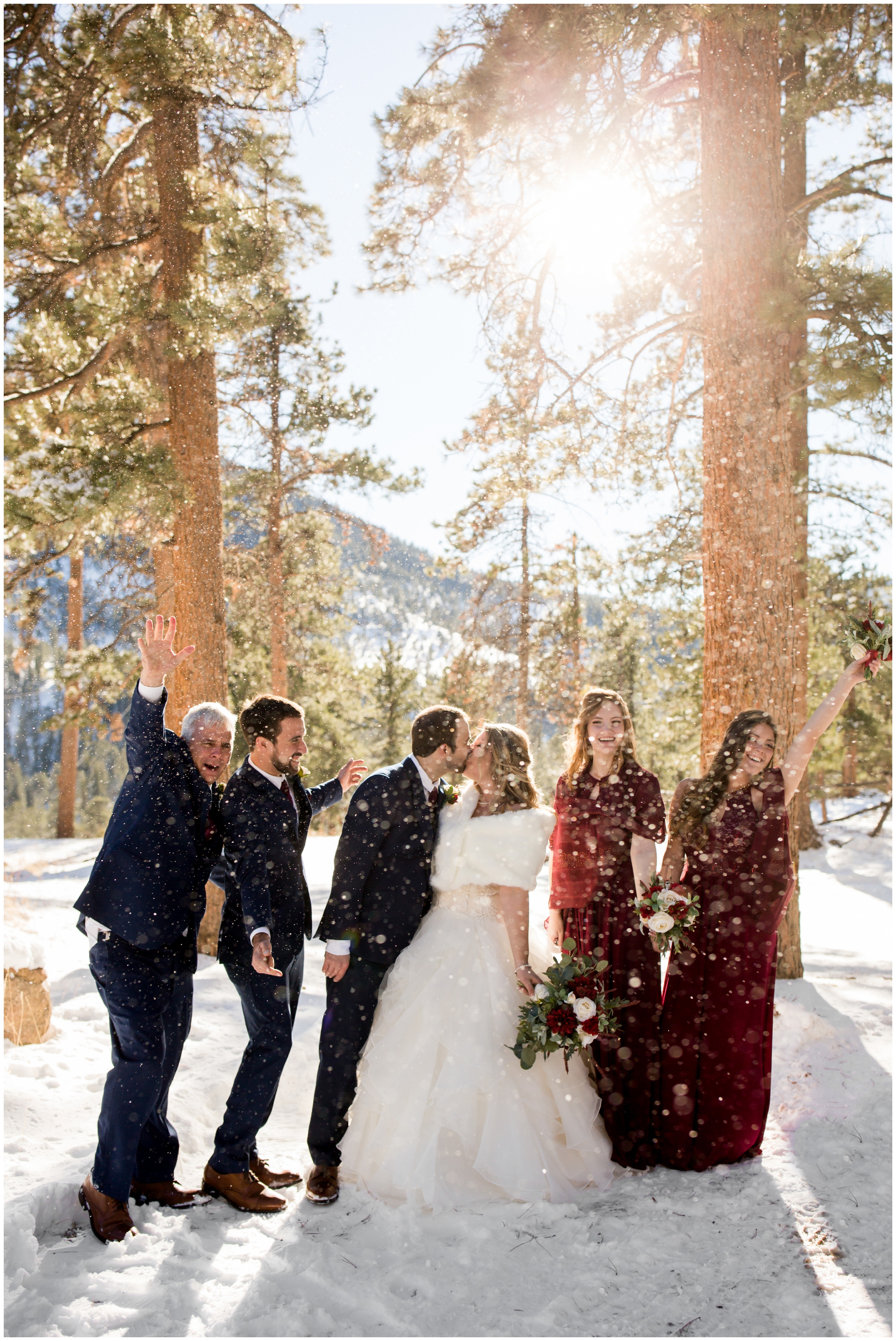 bridal party in red and navy blue with snow falling during Estes Park Colorado wedding pictures 