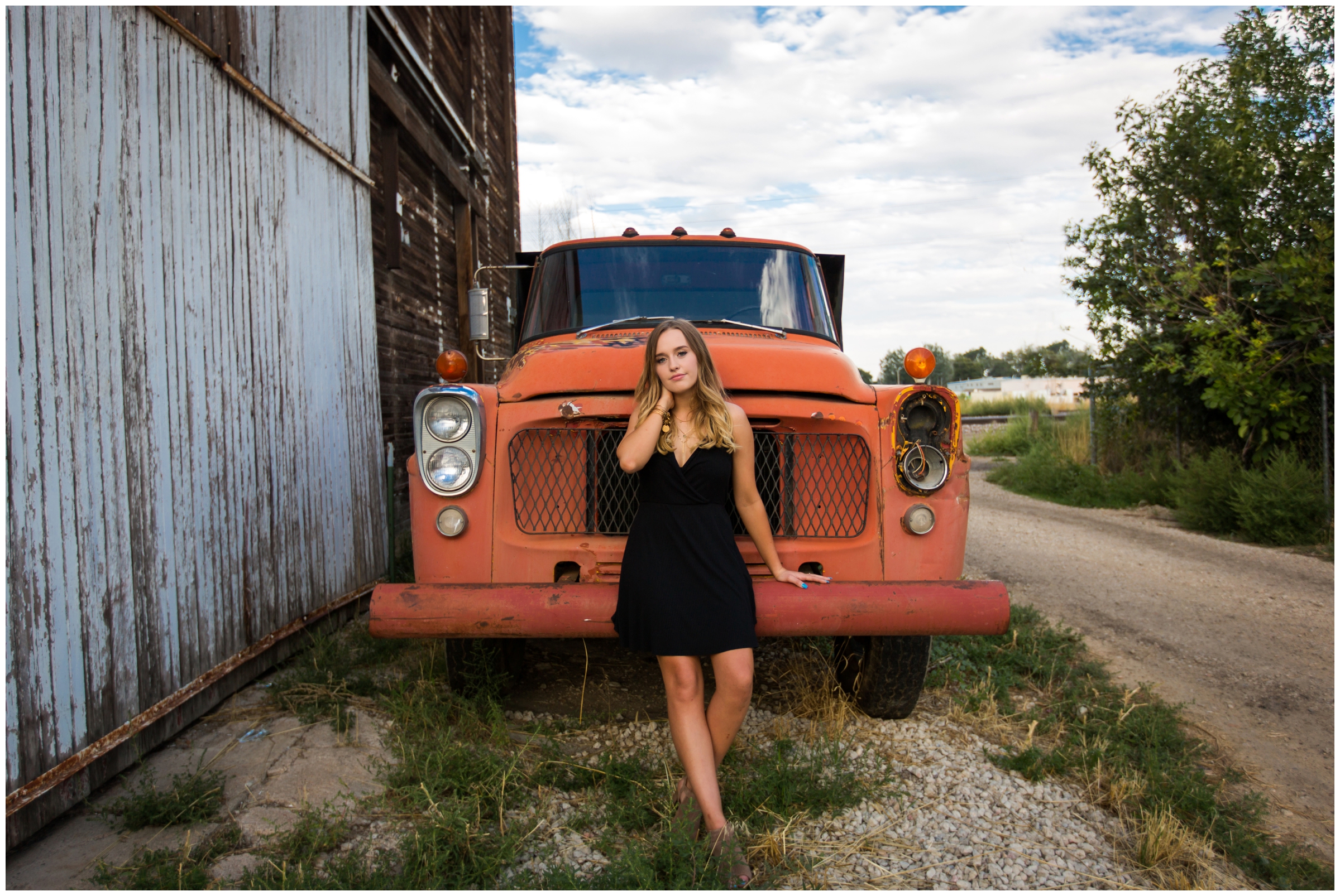 teen girl sitting on old orange truck at Berthoud Colorado senior portraits 