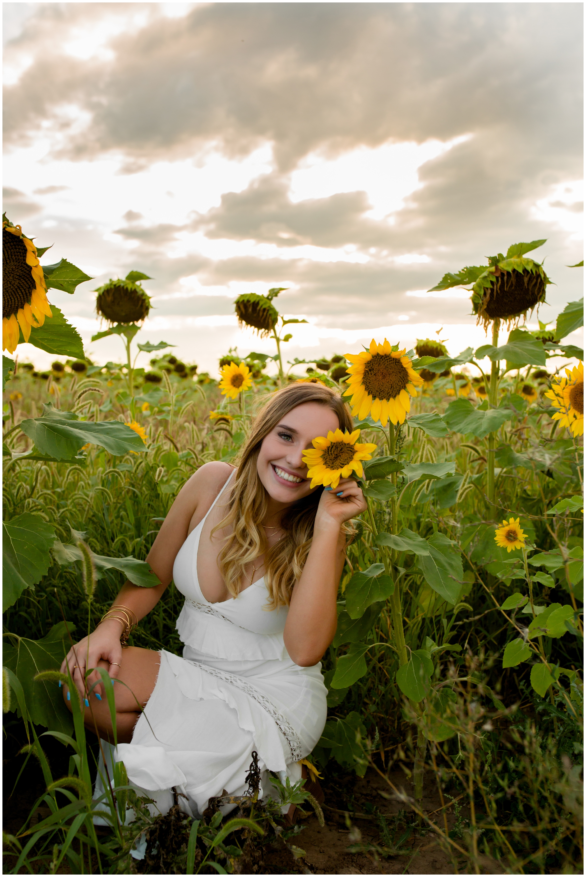 teen girl holding sunflower over eye during skyline high school longmont colorado senior pictures 