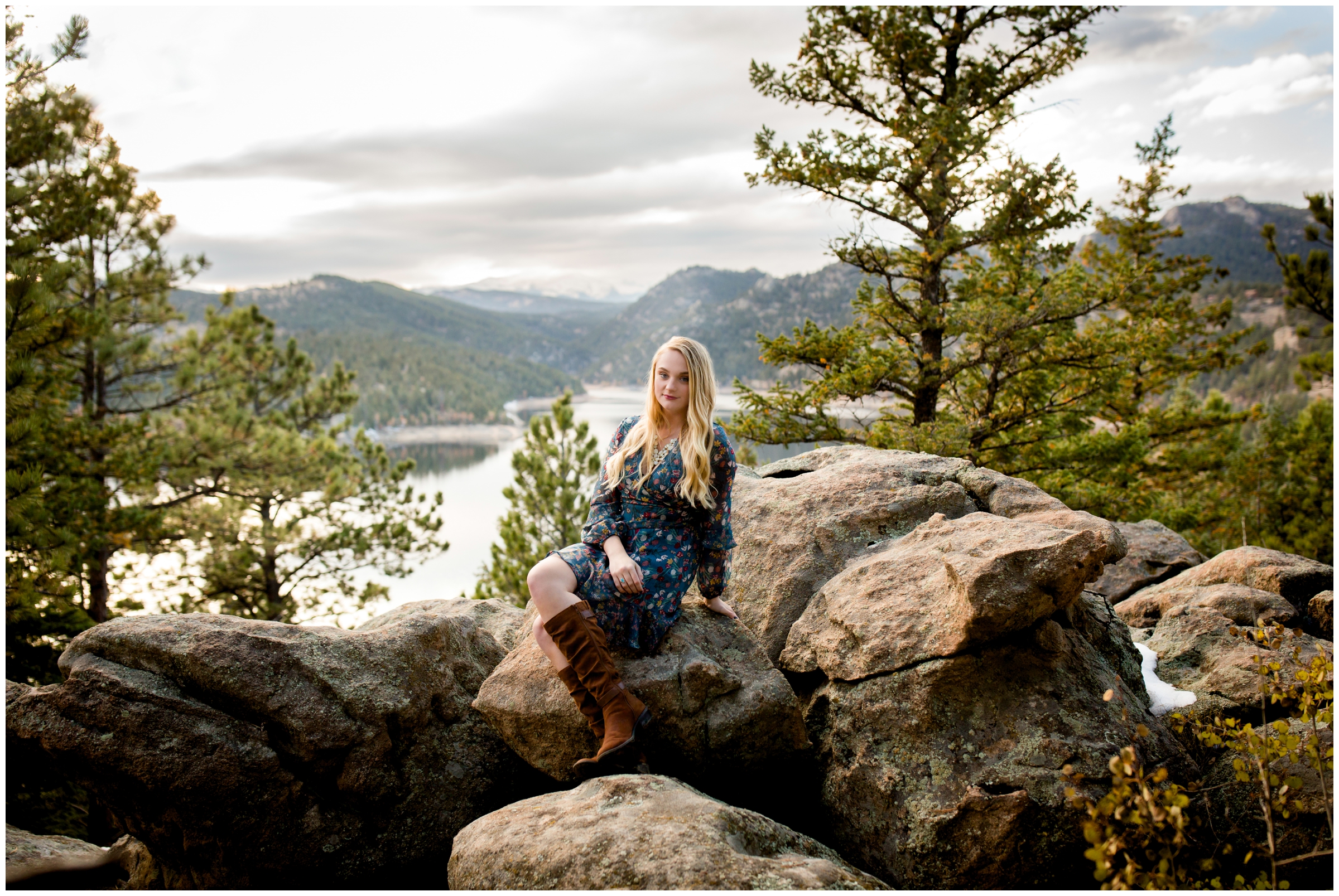 teen girl sitting on large rocks with mountain lake in background 
