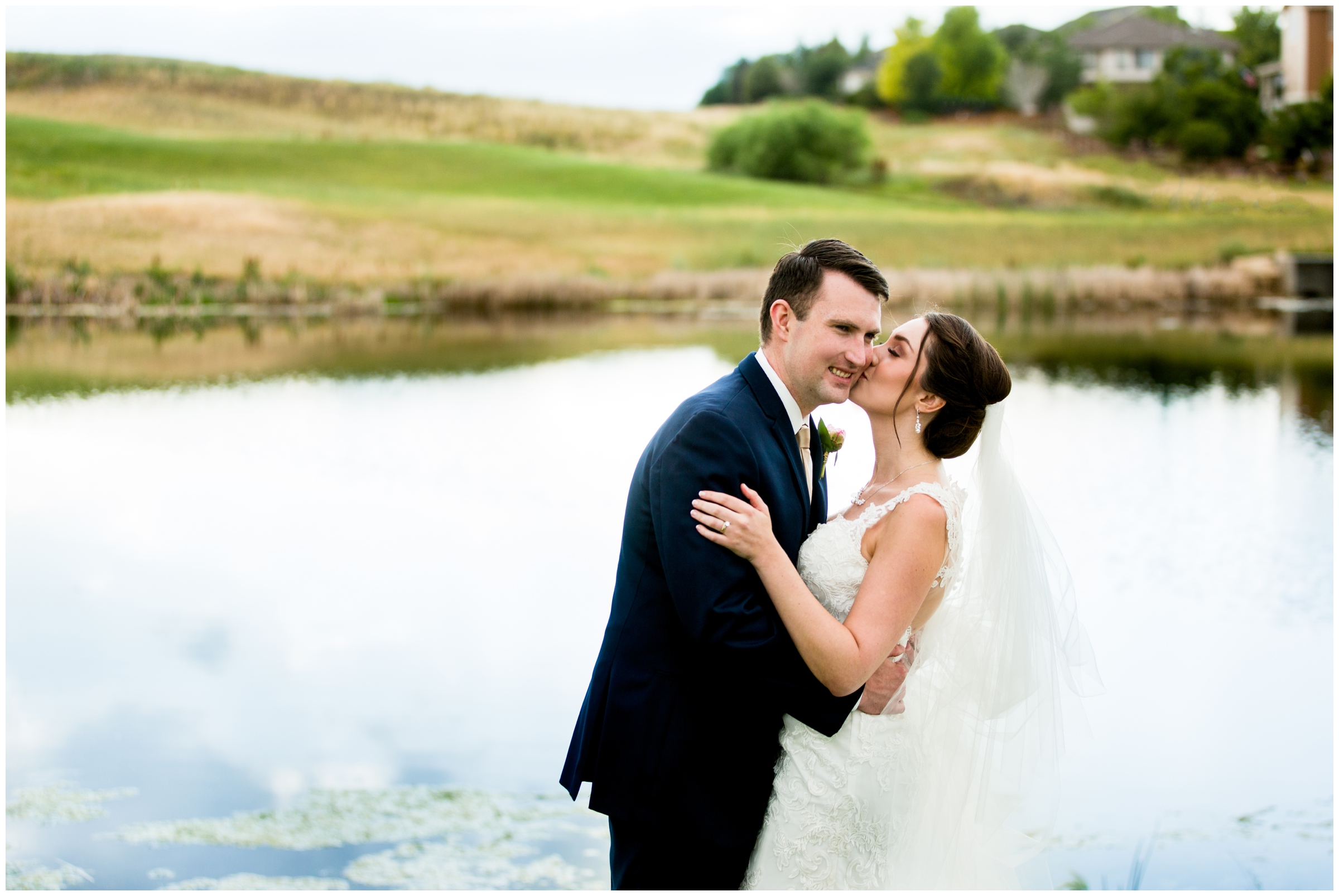 couple kissing by lake during Denver Colorado golf course wedding pictures 
