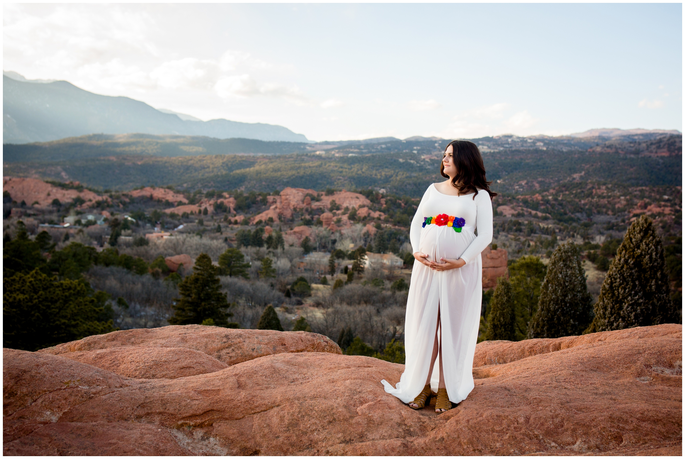 pregnant women holding belly with pikes peak in background at Colorado Springs maternity photos 