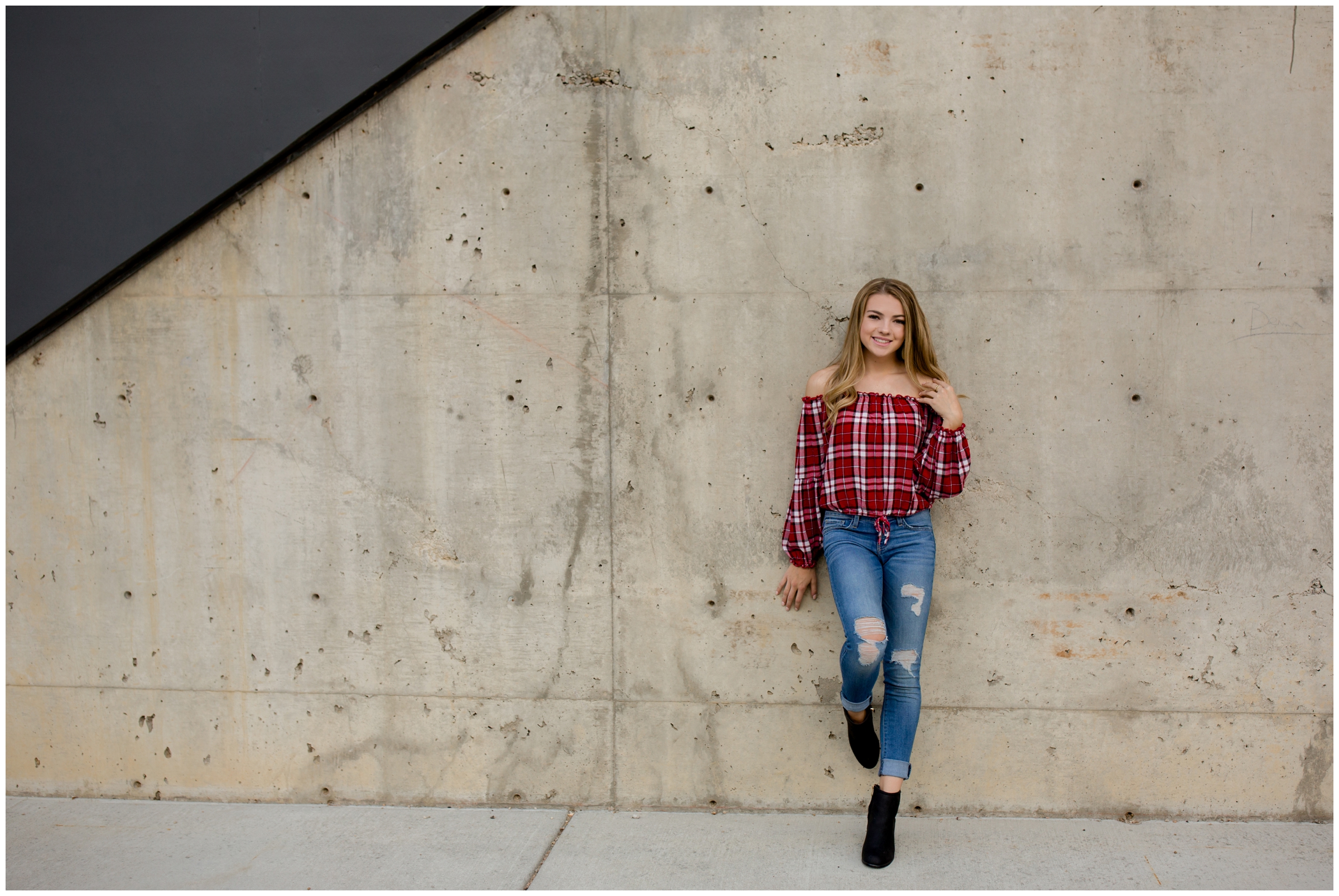teen girl leaning against concrete wall at urban Longmont Colorado senior portraits 
