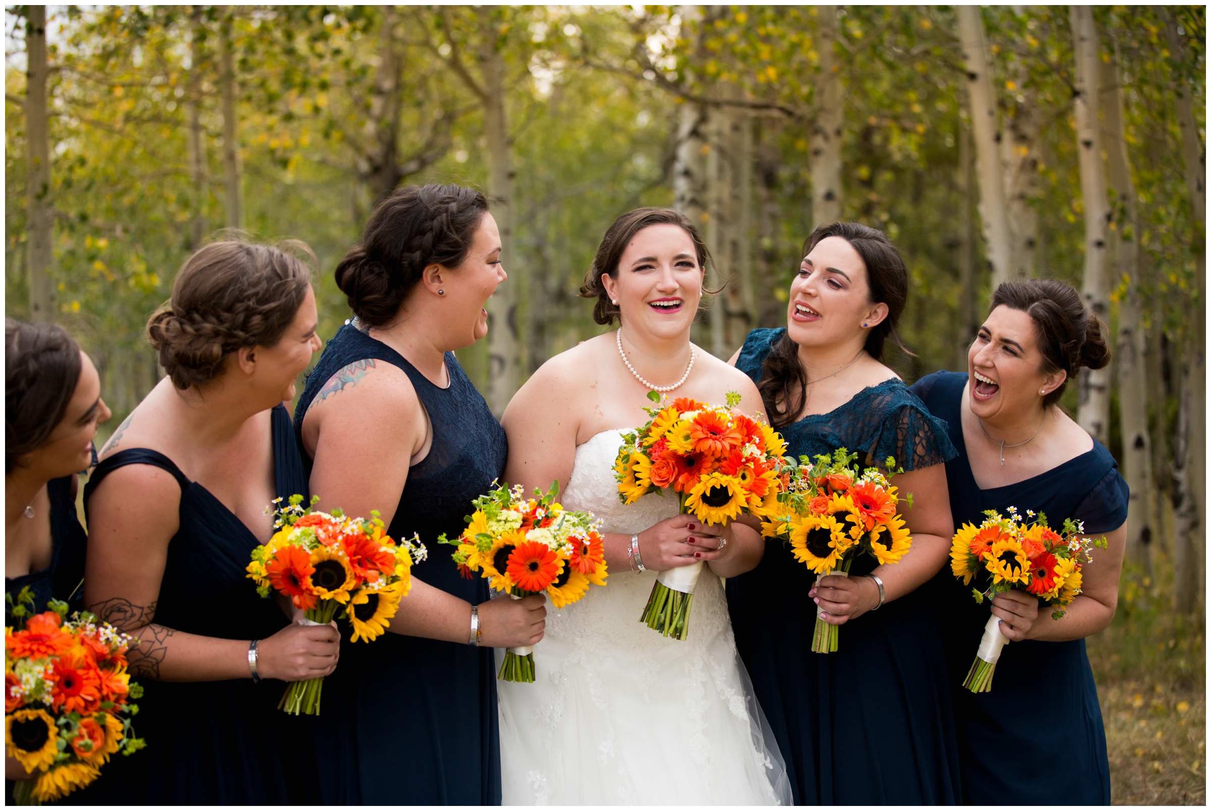 bridesmaids in long blue dresses with orange and yellow bouquets