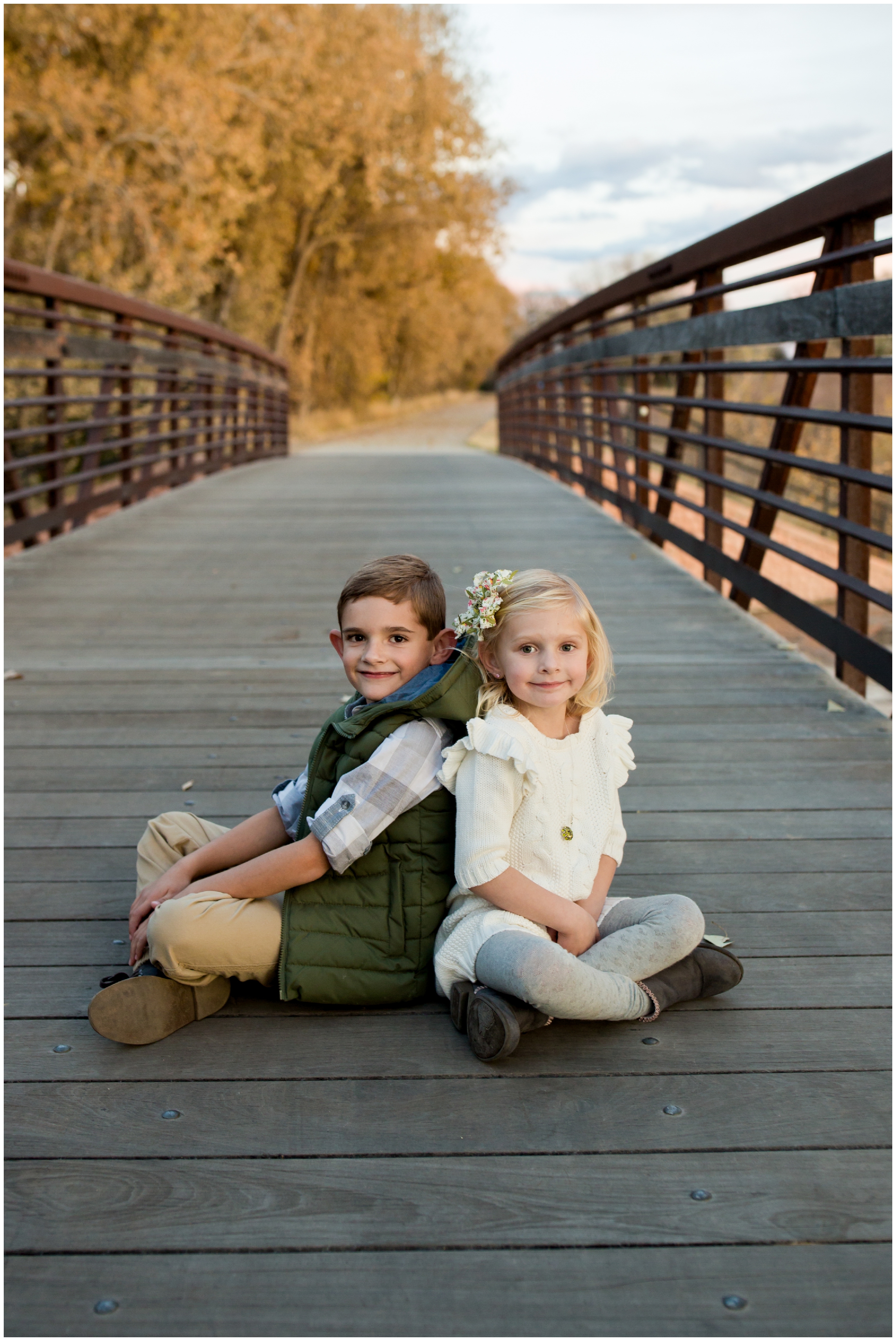 kids sitting on bridge at Colorado fall family photos at Golden Ponds Longmont