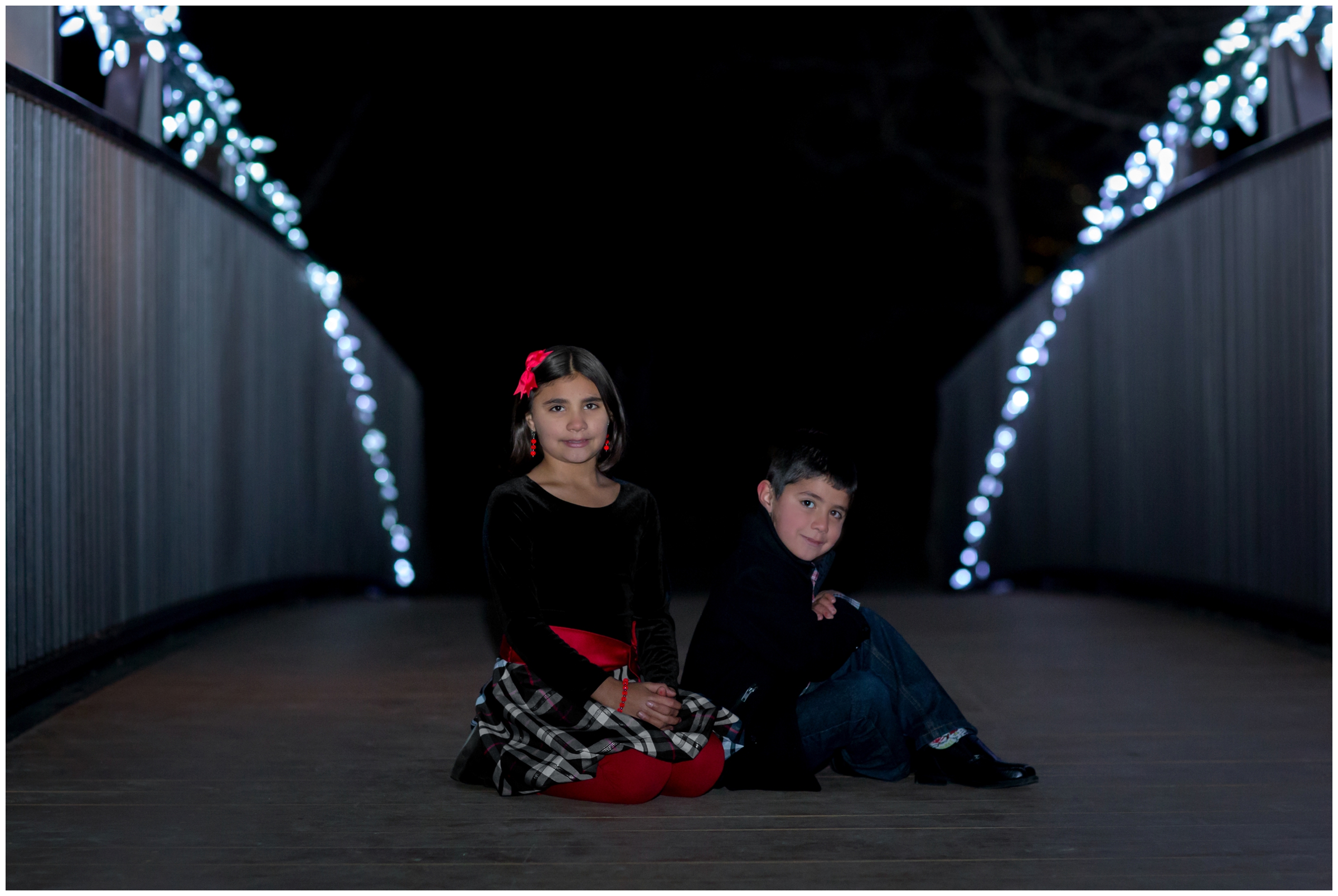 kids sitting on a bridge at nighttime at Winter Wonderlights Chapungu Sculpture Garden 