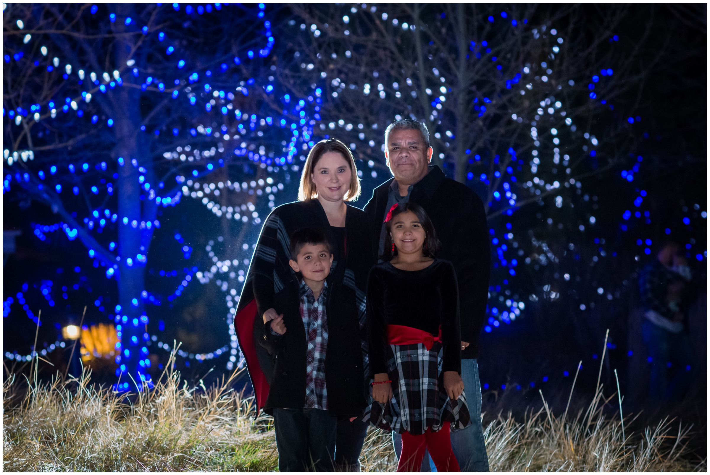 winter Colorado family portraits at night with blue holiday lights 