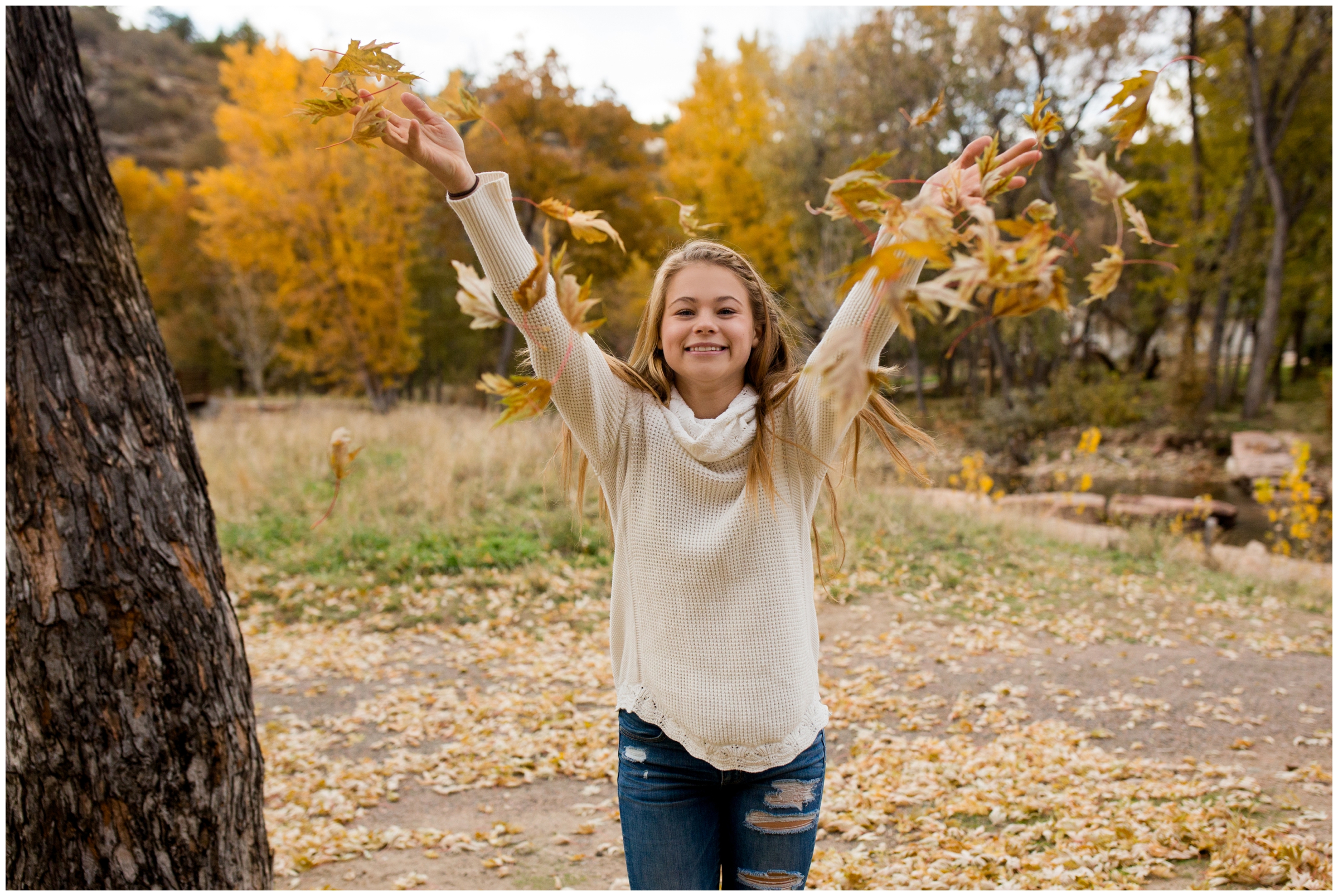 teen girl throwing leaves during fall Colorado senior portraits