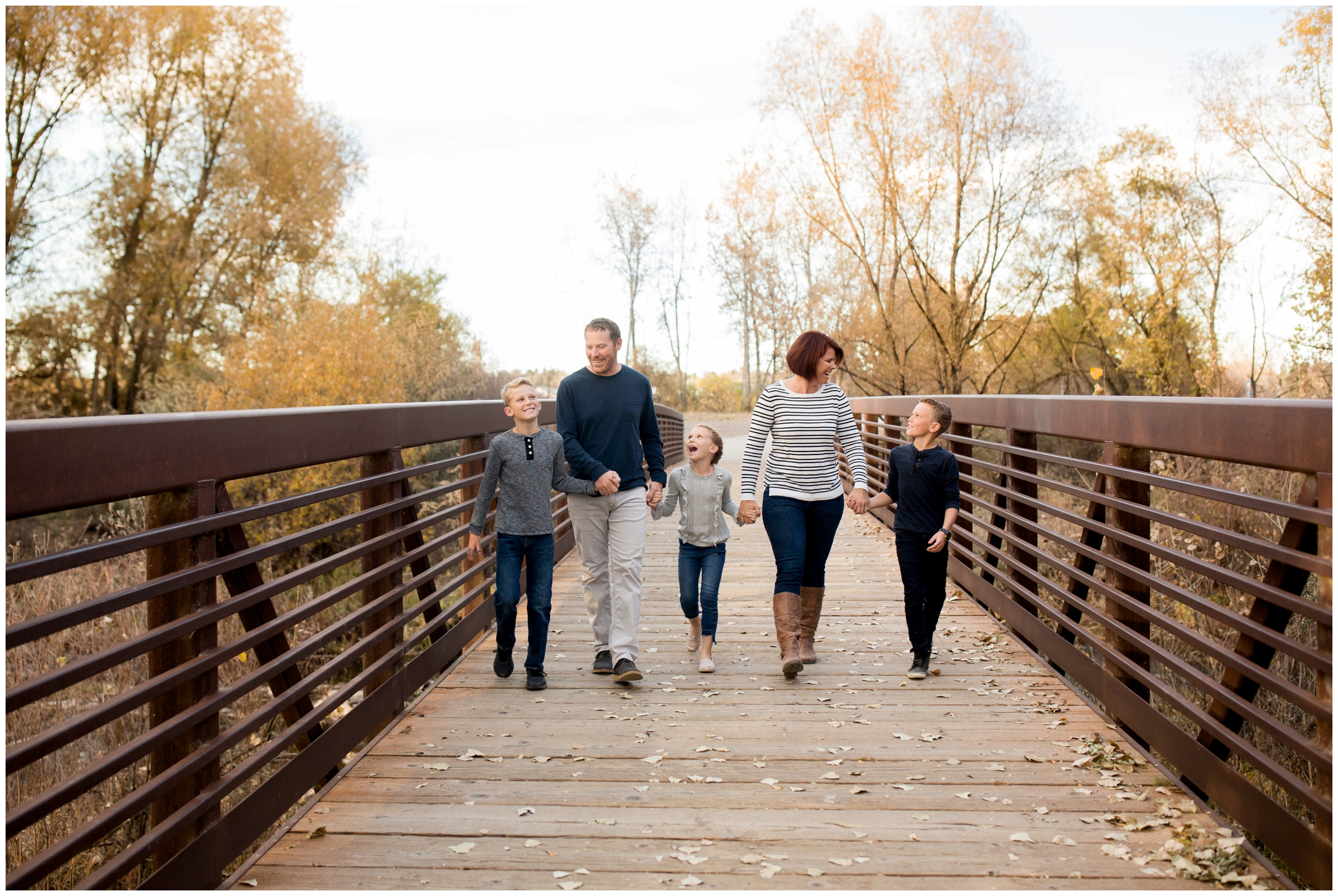 family walking on bridge candidly during Boulder County family photos at Golden Ponds by Longmont Colorado portrait photographer Plum Pretty Photography