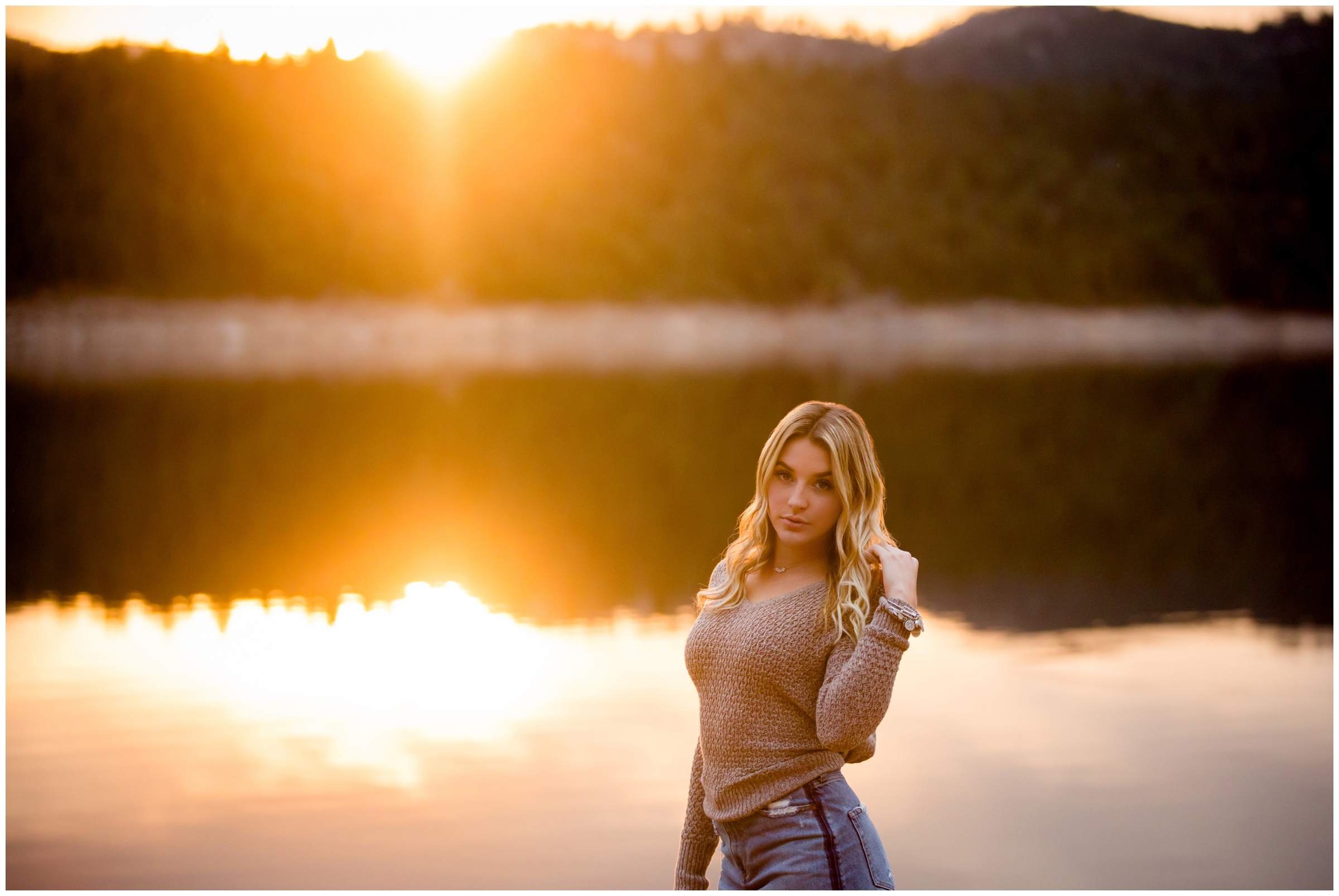 teen girl posing by lake with colorful sunset in background during Frederick Colorado senior pictures 