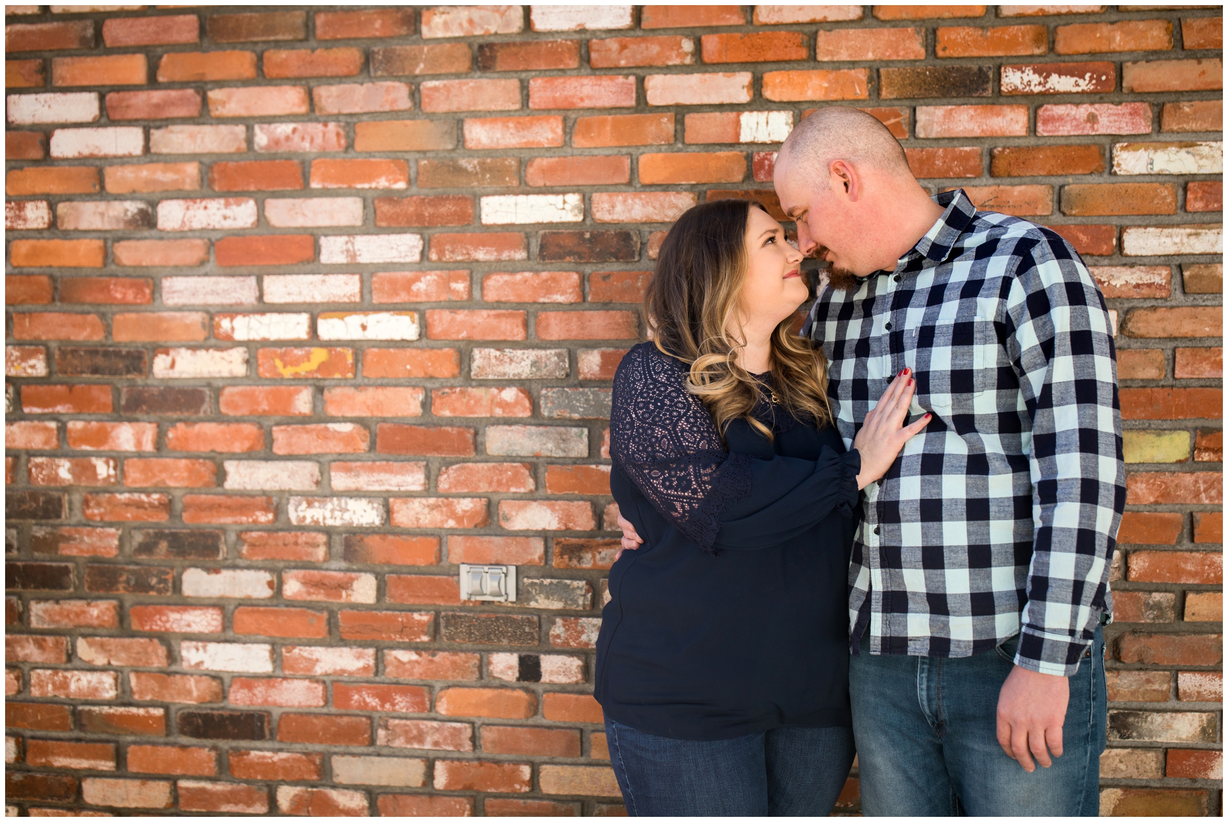 couple in front of brick wall during urban Colorado engagement pictures 