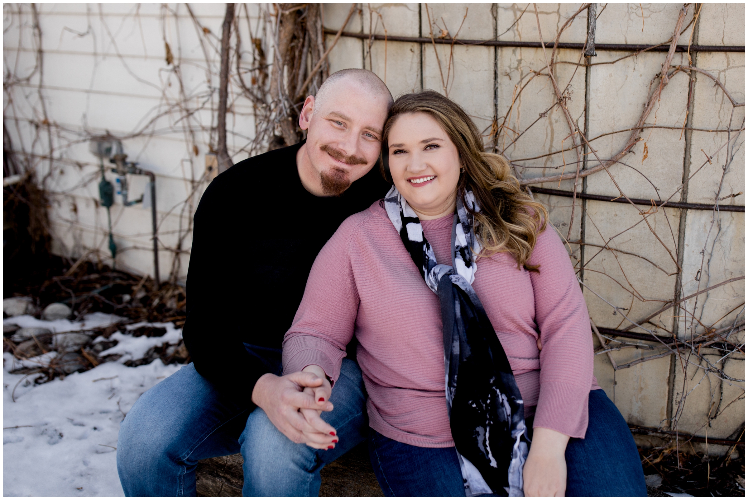 couple sitting in front of silo at Colorado winter engagement pictures 