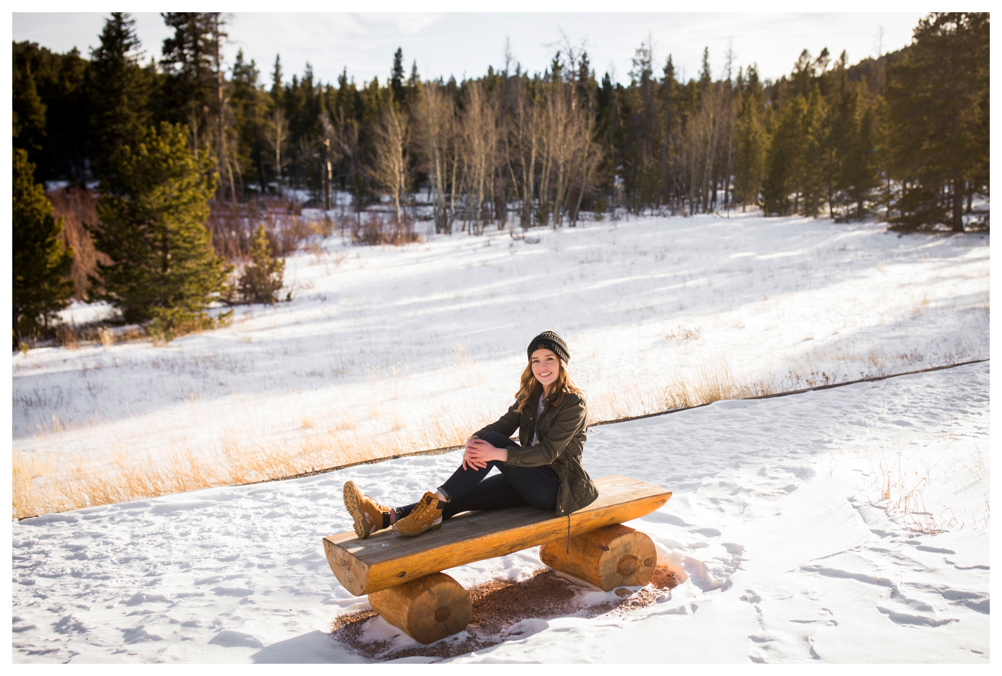 teen girl sitting on bench with snow all around at Lily Lake RMNP
