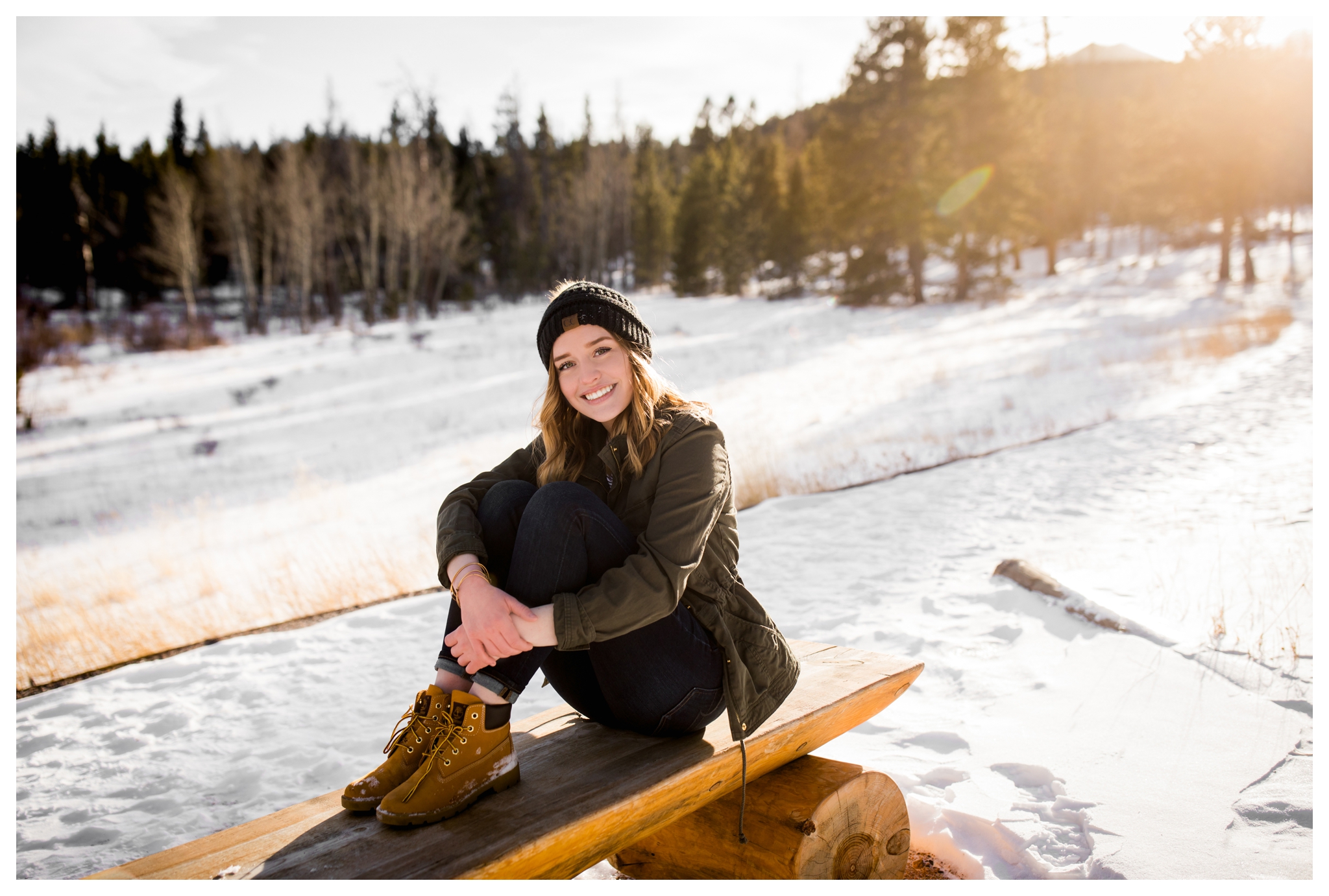 teen posing on bench with snow all over during winter senior pictures in Estes Park Colorado