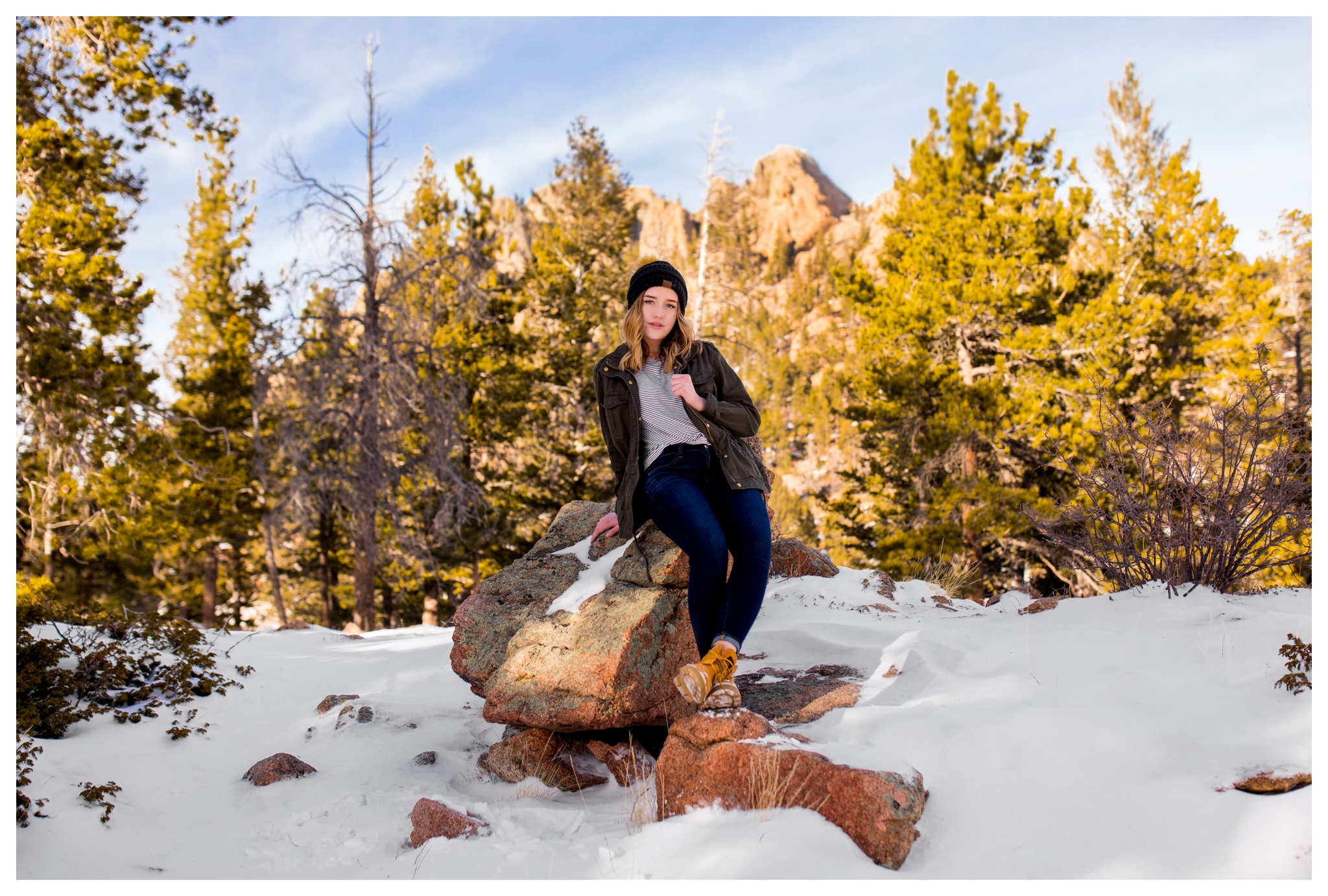 teen girl sitting on rock with mountains in background at Lily Lake Estes Park  