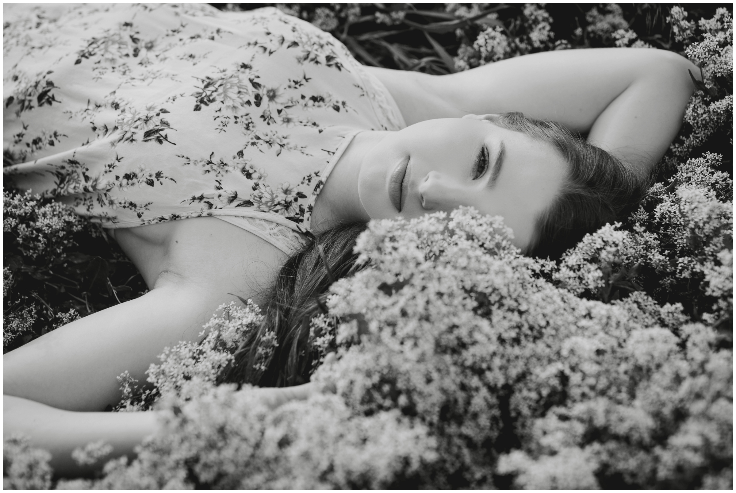black and white photo of teen laying in flower field during senior photos by best Colorado portrait photographer Plum Pretty Photo