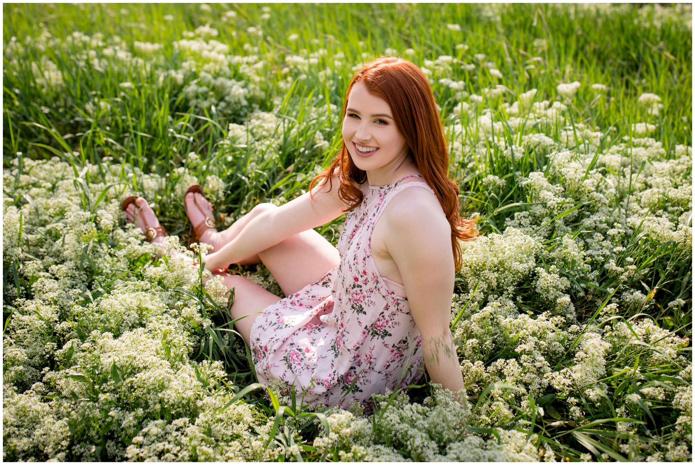 redhead high school senior sitting in field of flowers during Erie Colorado senior pictures 