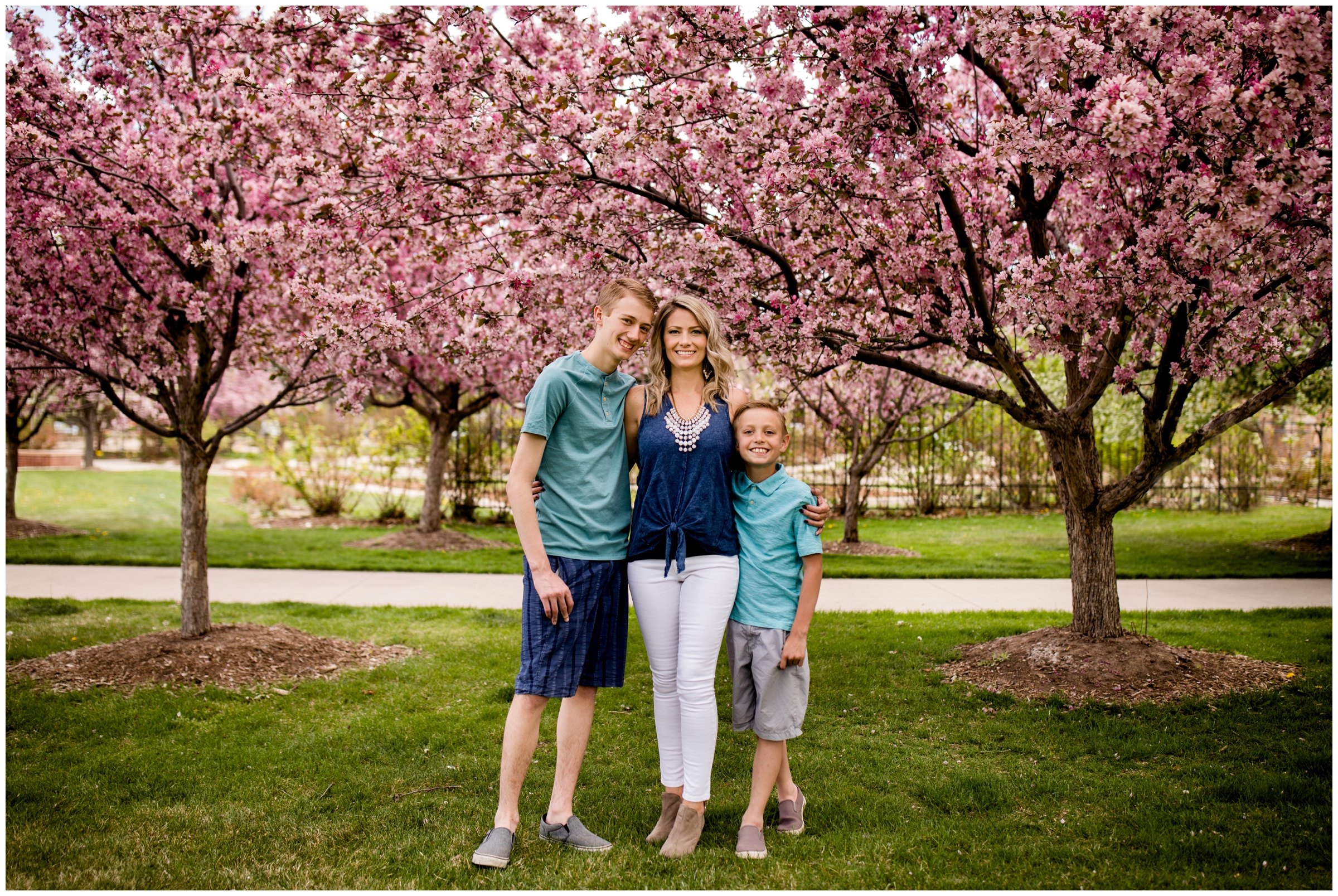 boys posing with their mom under cherry blossom trees during Longmont family photography session 