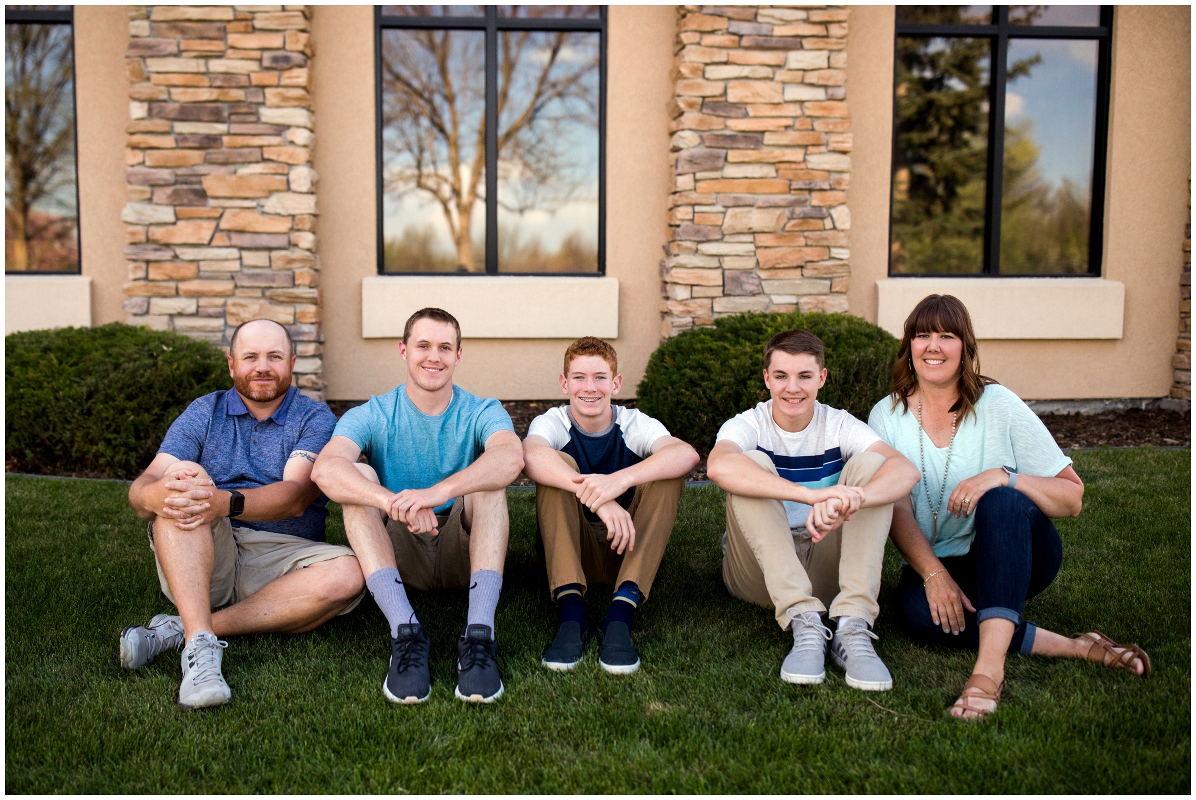 family sitting in the grass during Longmont family photography session at local park