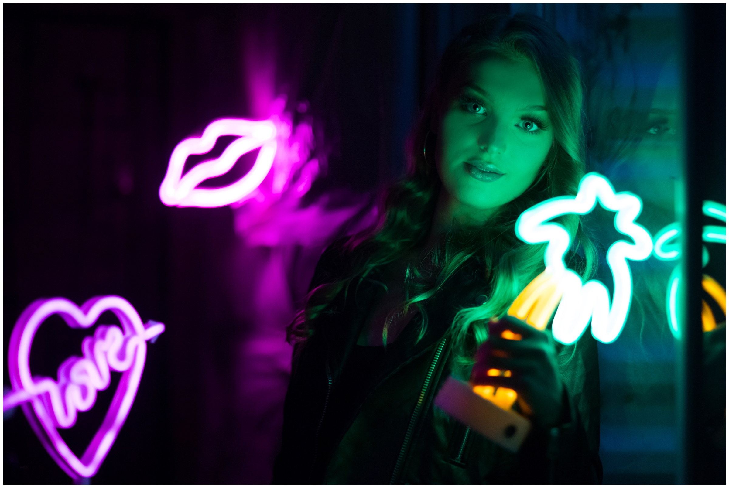 teen girl leaning against window holding neon sign during creative Colorado modeling pictures 