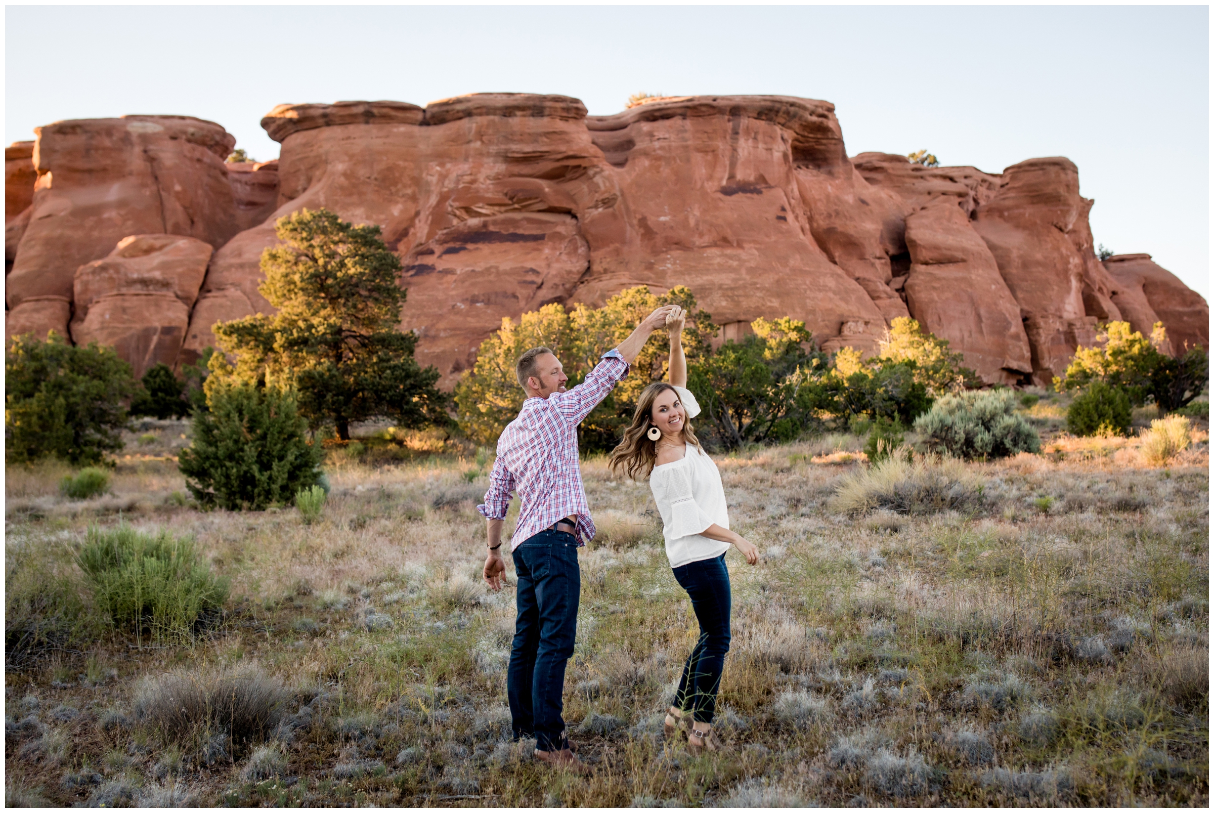 couple dancing with red rock formations in background during Colorado engagement pictures 