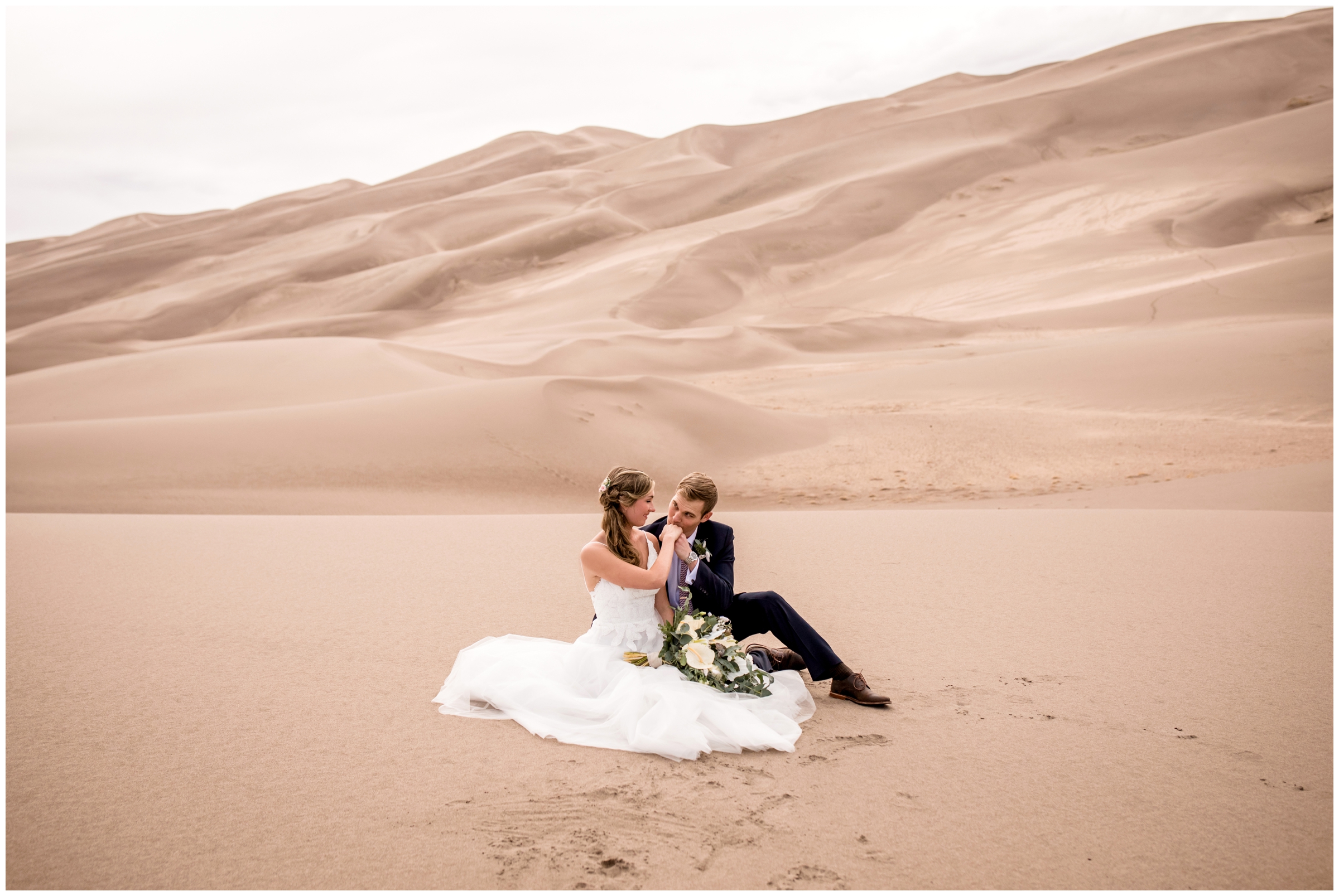 couple sitting on sand during Colorado adventure elopement at Great Sand Dunes Park