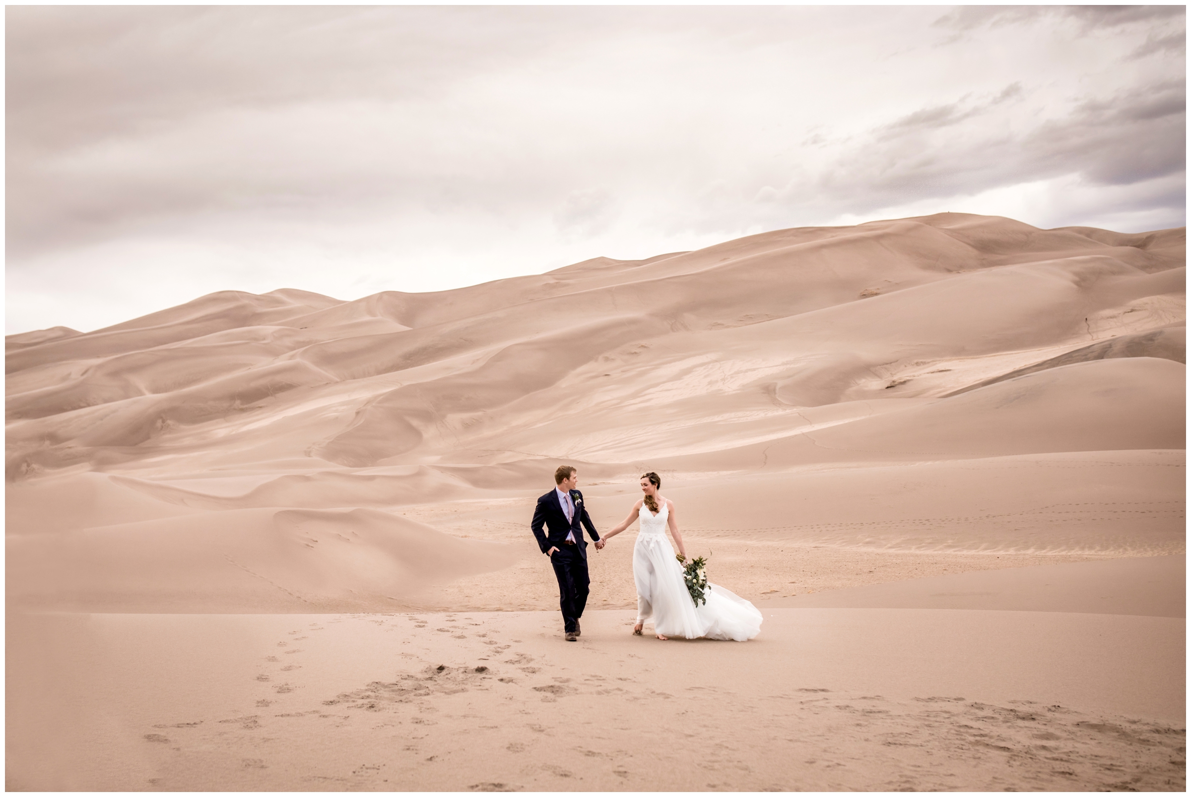couple walking through the Colorado sand dunes during their elopement wedding portraits 