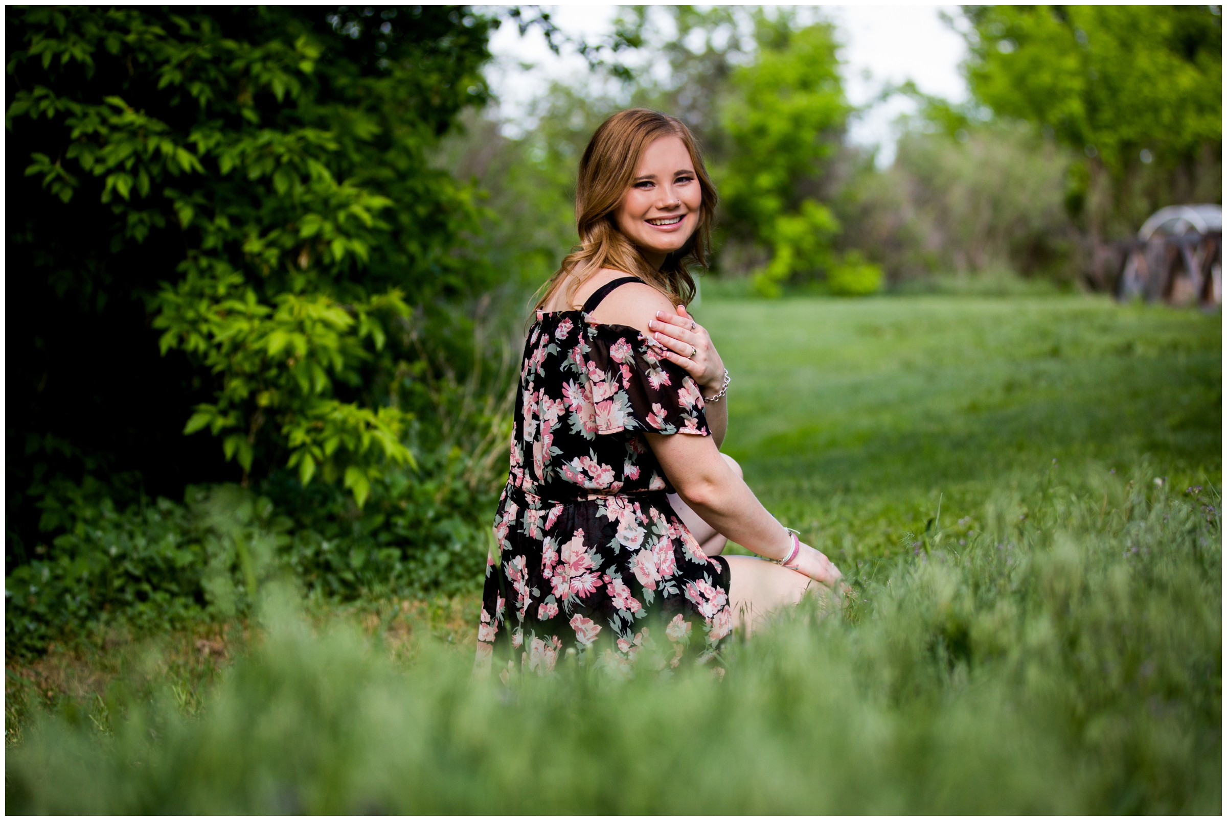 teen girl squatting in grass during Colorado summer portrait photography session 