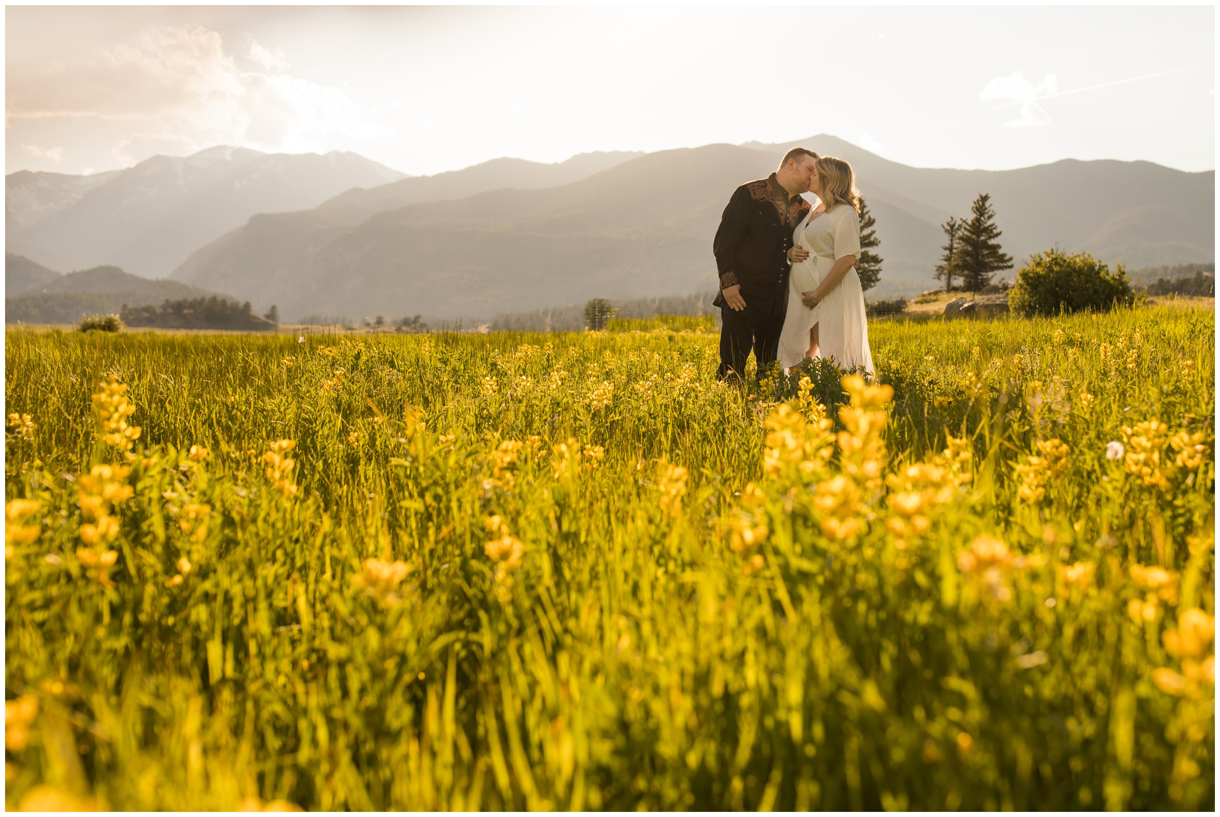 couple kissing in wildflower field during Estes Park maternity pictures 