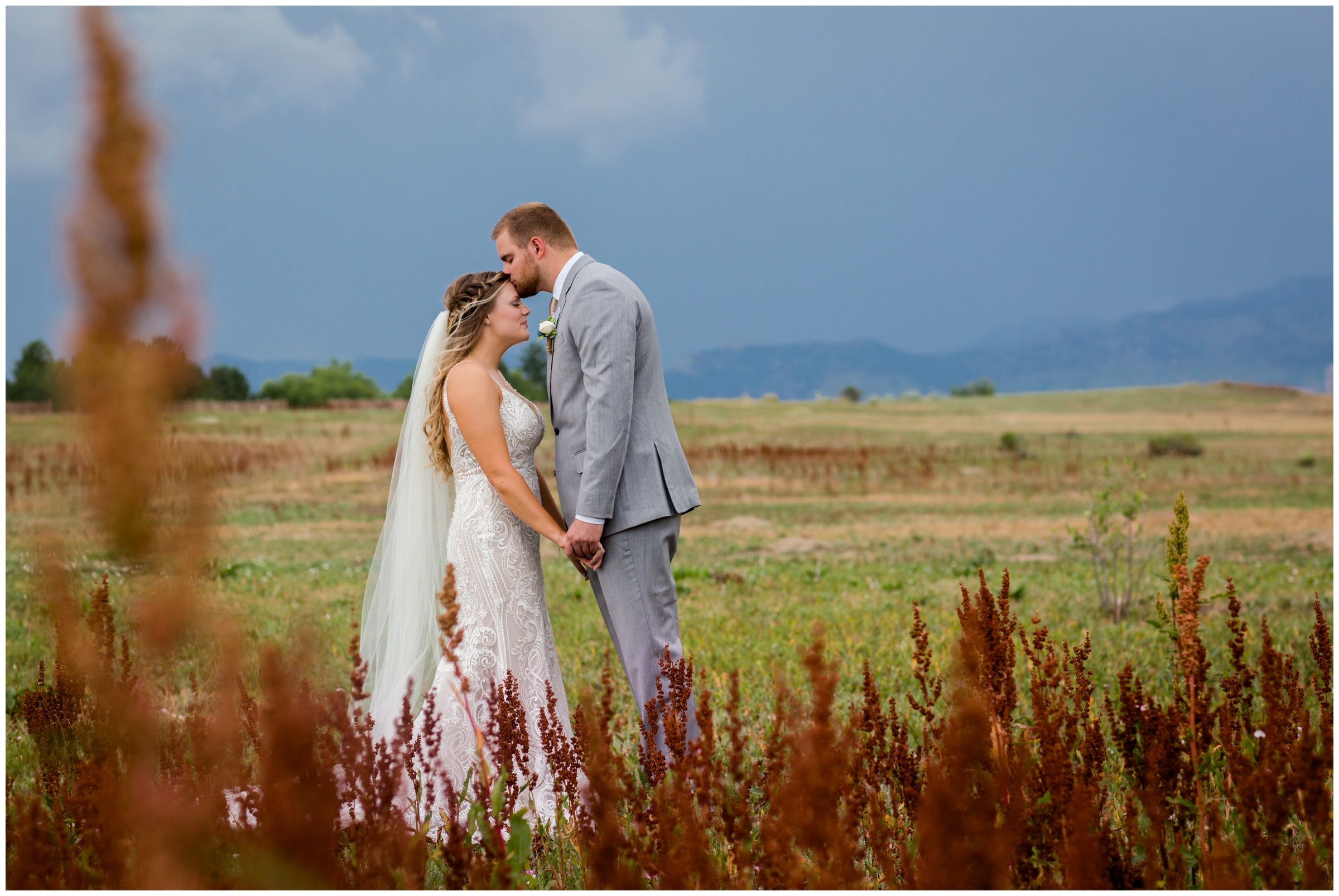 couple kissing in front of indian paintbrush flowers during Colorado lake wedding photos