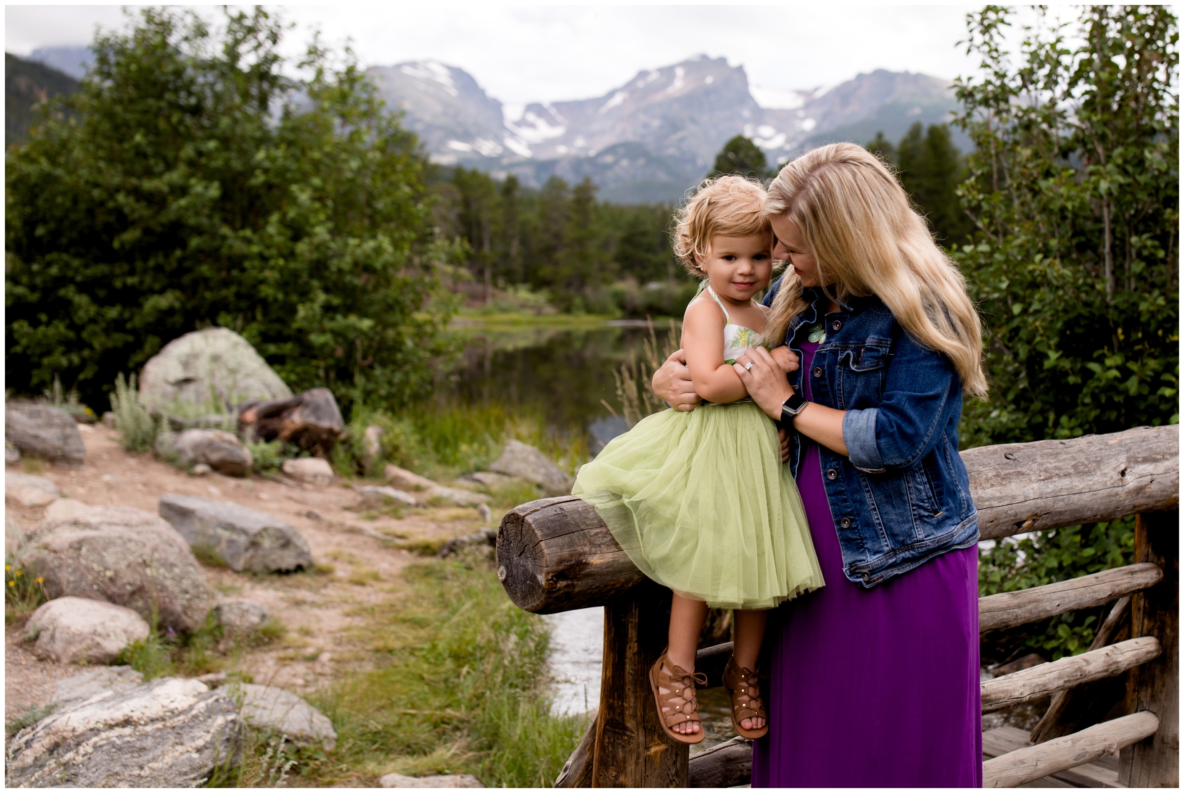 mom and toddler girl posing on bridge during Estes Park family portraits in RMNP