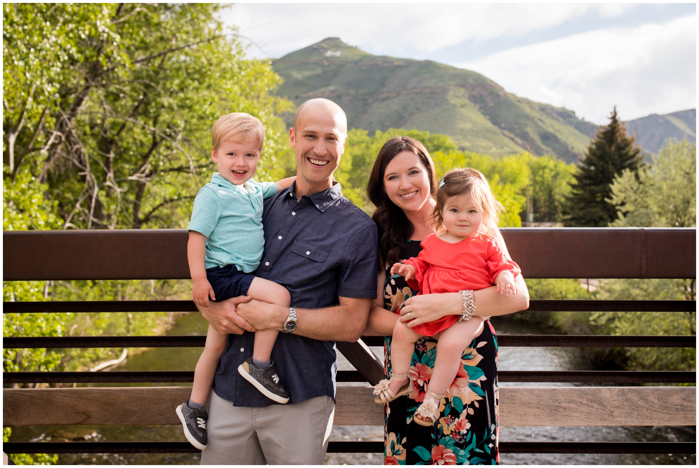 family standing on bridge with mountains in background during Colorado portrait photography session 