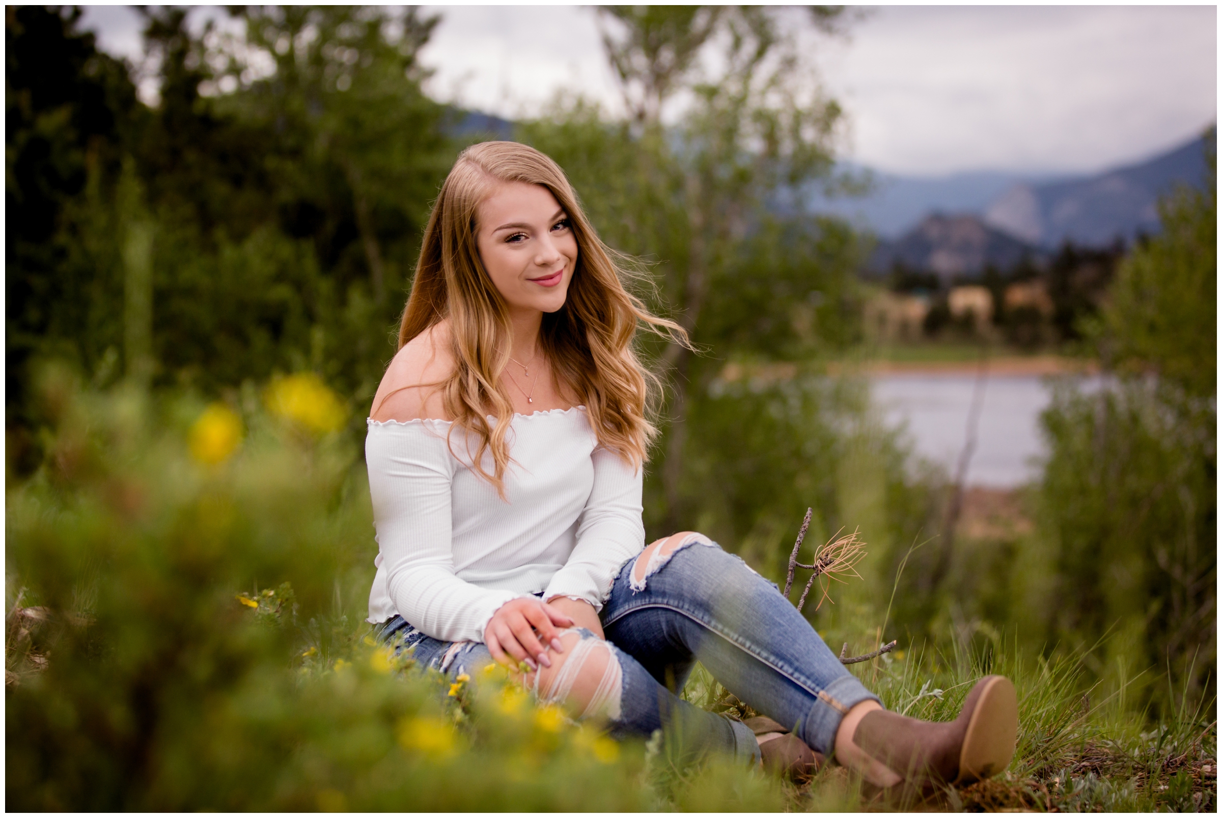 teen girl sitting in flower field during Estes Park Colorado senior photos 