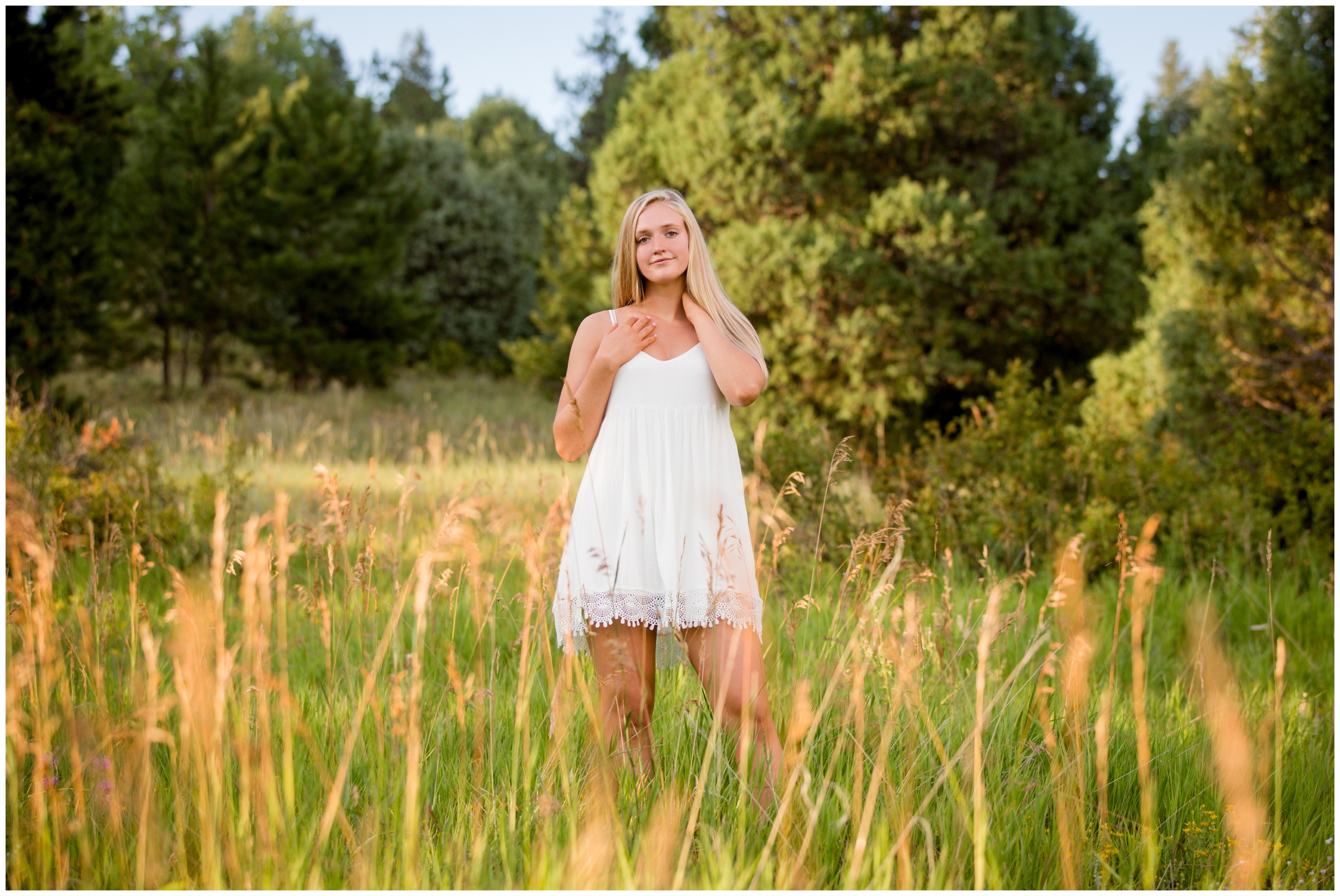 teen in white dress posing in mountain field 