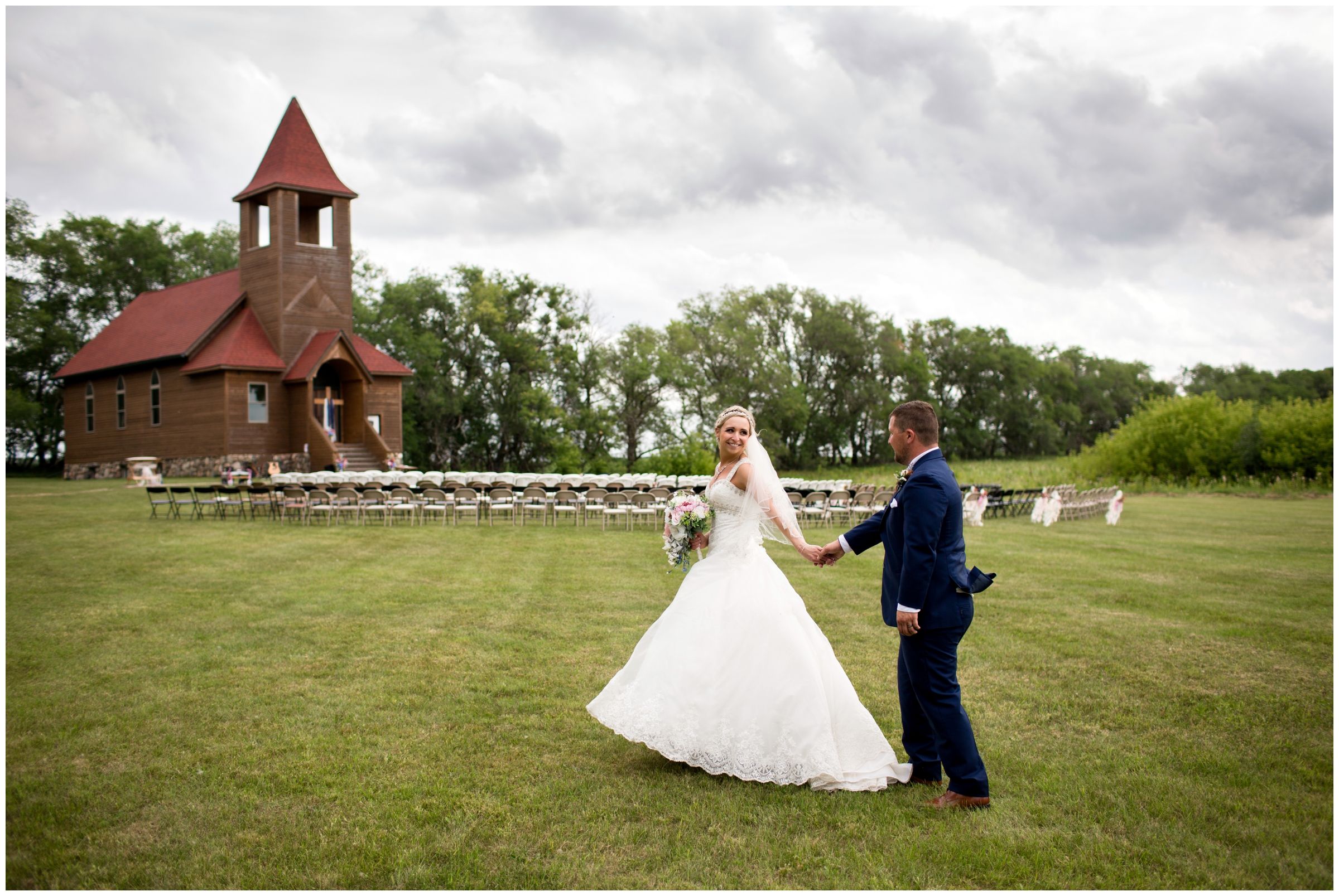 couple walking with chapel in background during rustic country wedding 